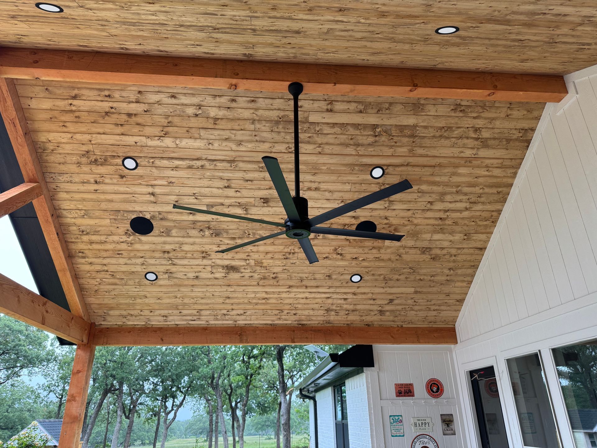 A ceiling fan is hanging from the ceiling of a wooden porch.