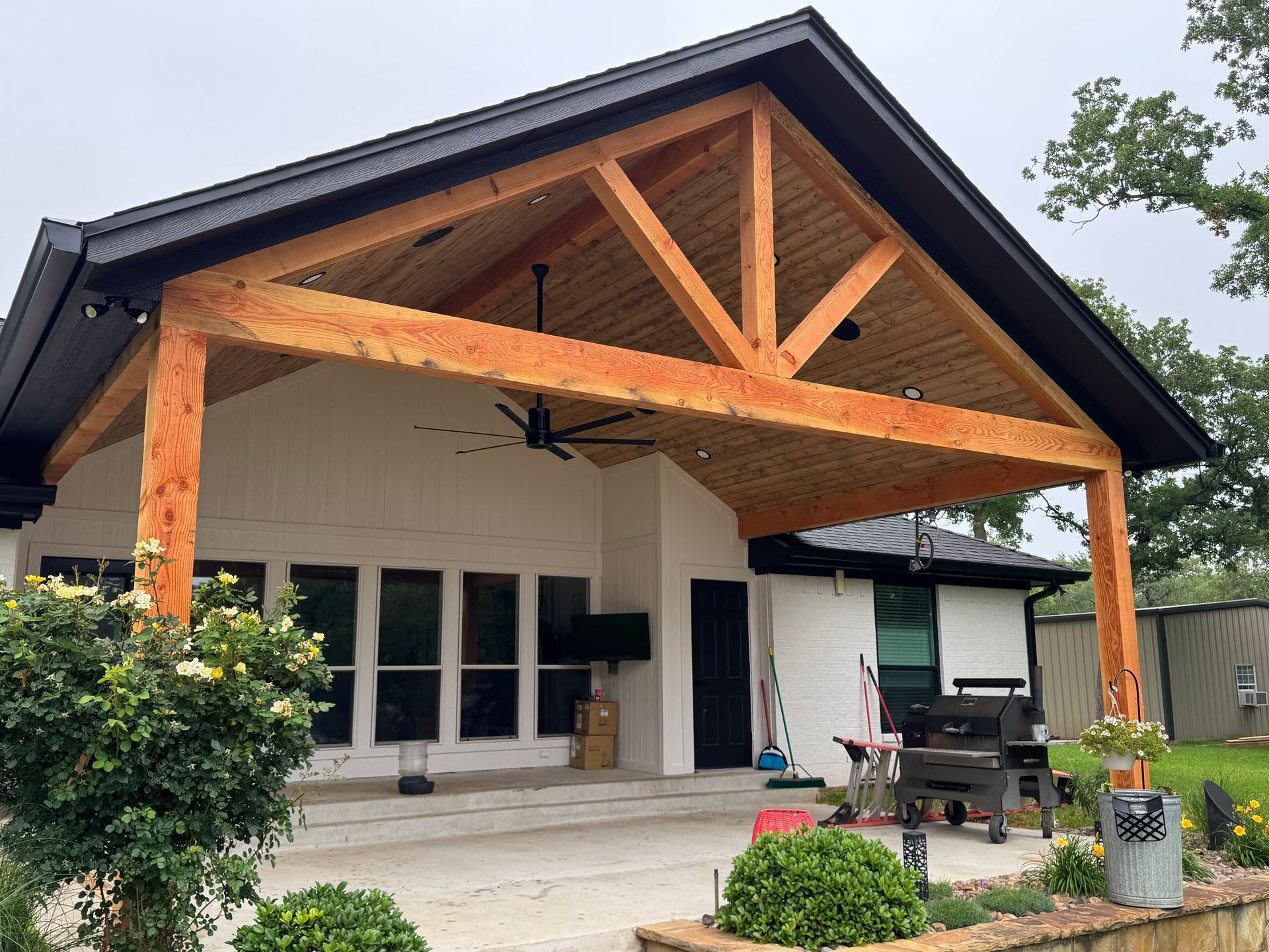 A white house with a wooden porch and a black roof.