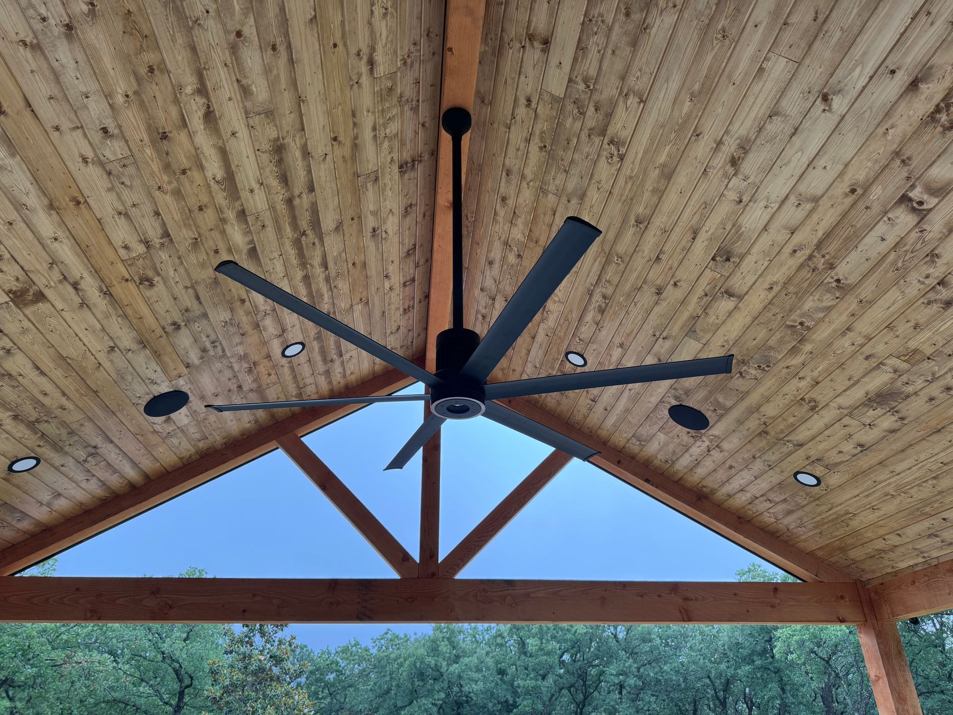 A ceiling fan is hanging from the ceiling of a wooden structure.