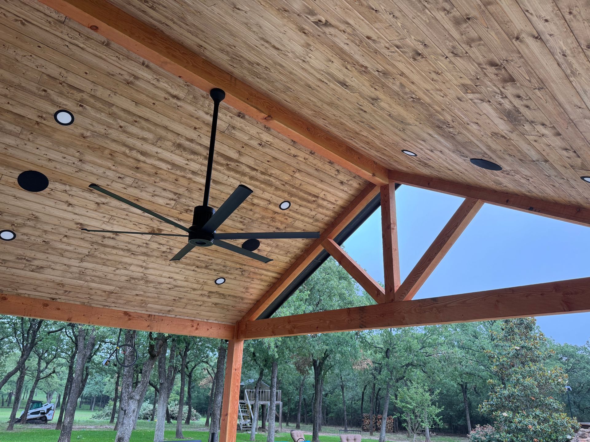 A ceiling fan is hanging from the ceiling of a wooden structure.