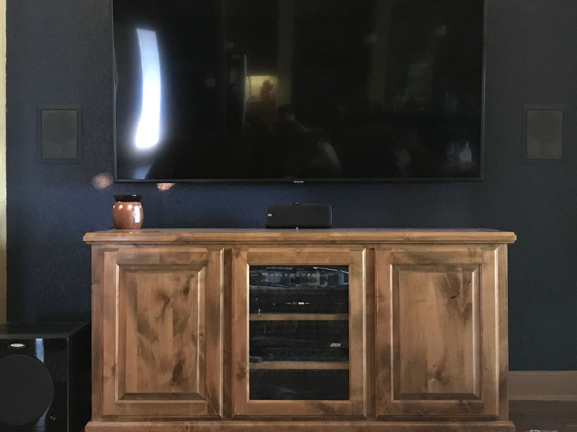 A large flat screen tv is mounted on the wall above a wooden entertainment center.