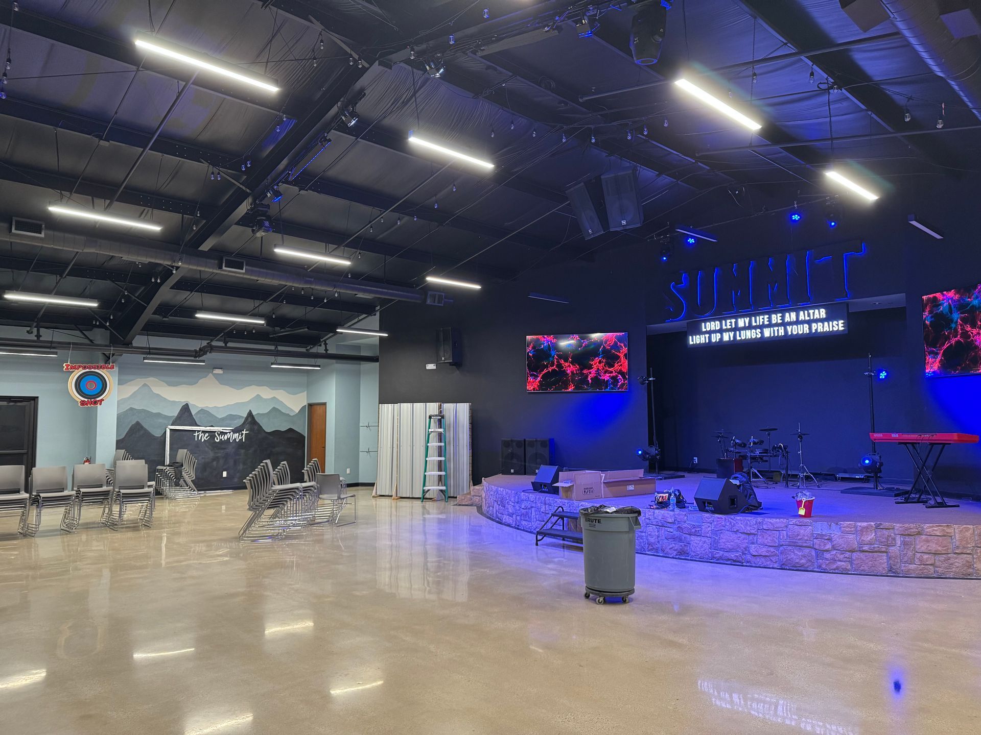 A large empty room with a stage and chairs in it.