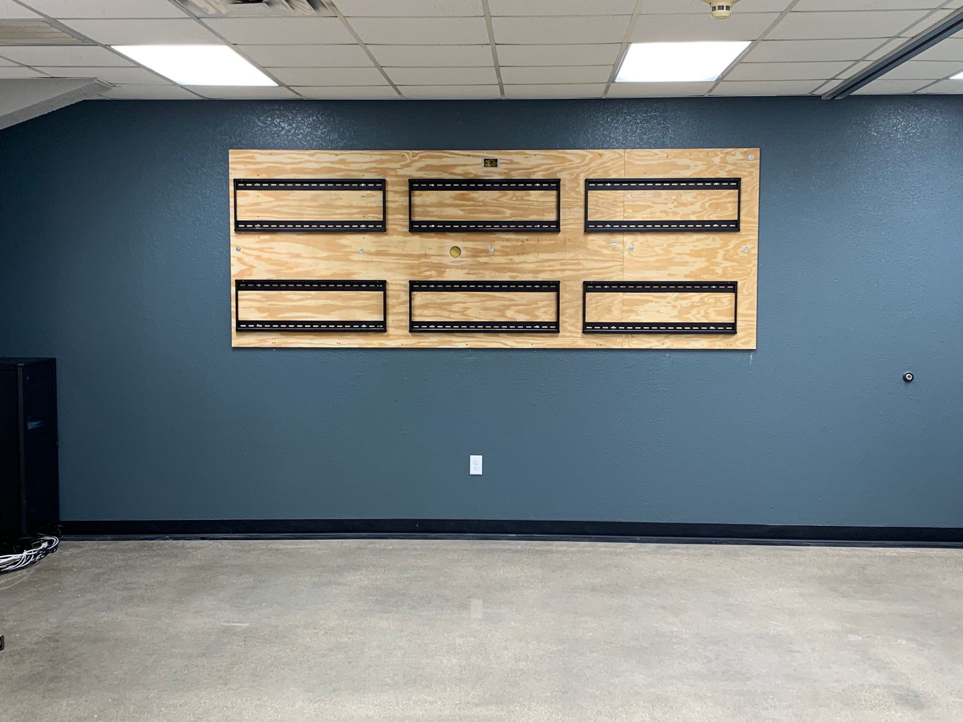 An empty room with a blue wall and a wooden wall mounted tv.