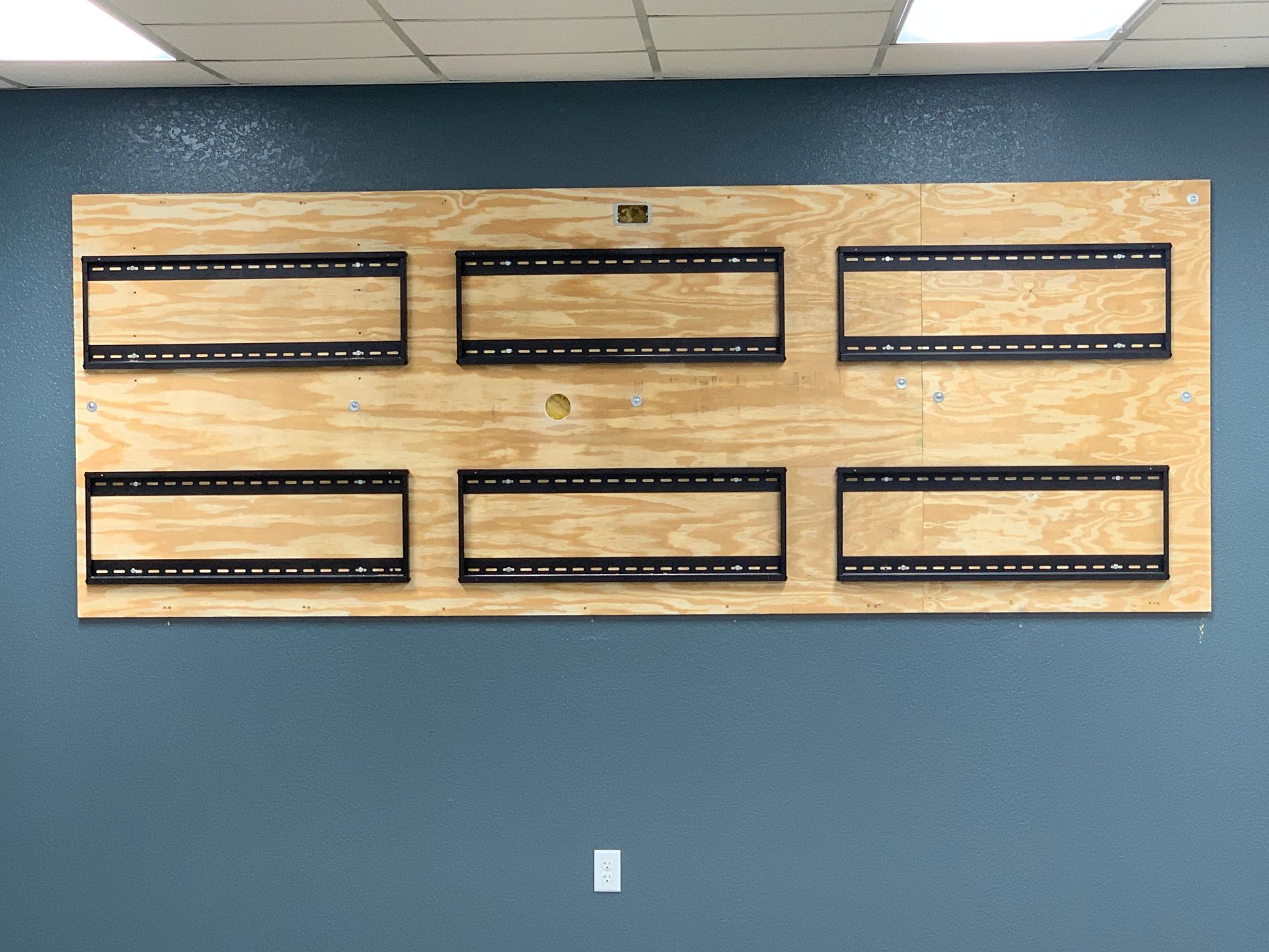 A large piece of wood with holes in it is hanging on a wall.