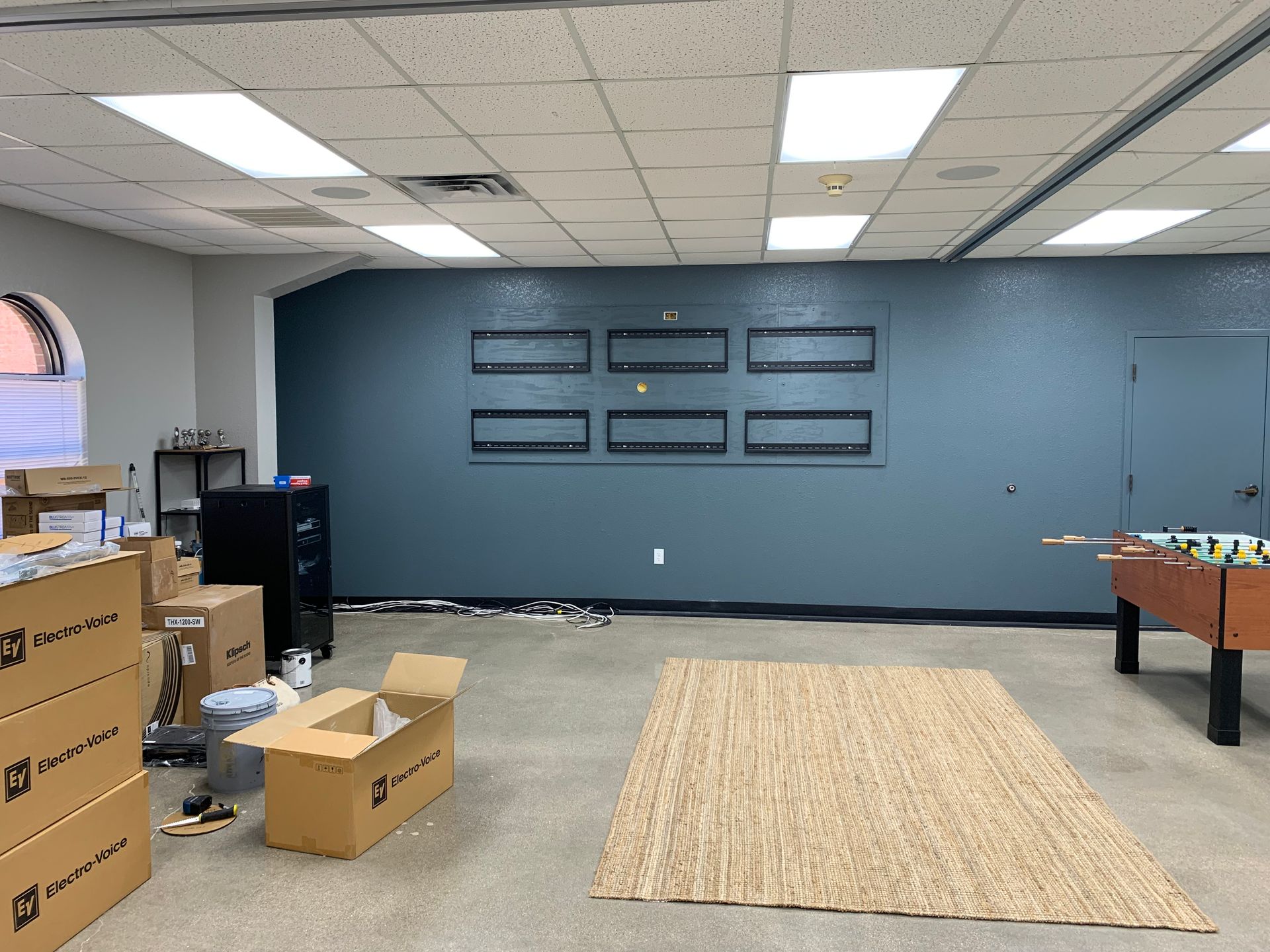 A room with a pool table and boxes on the floor.
