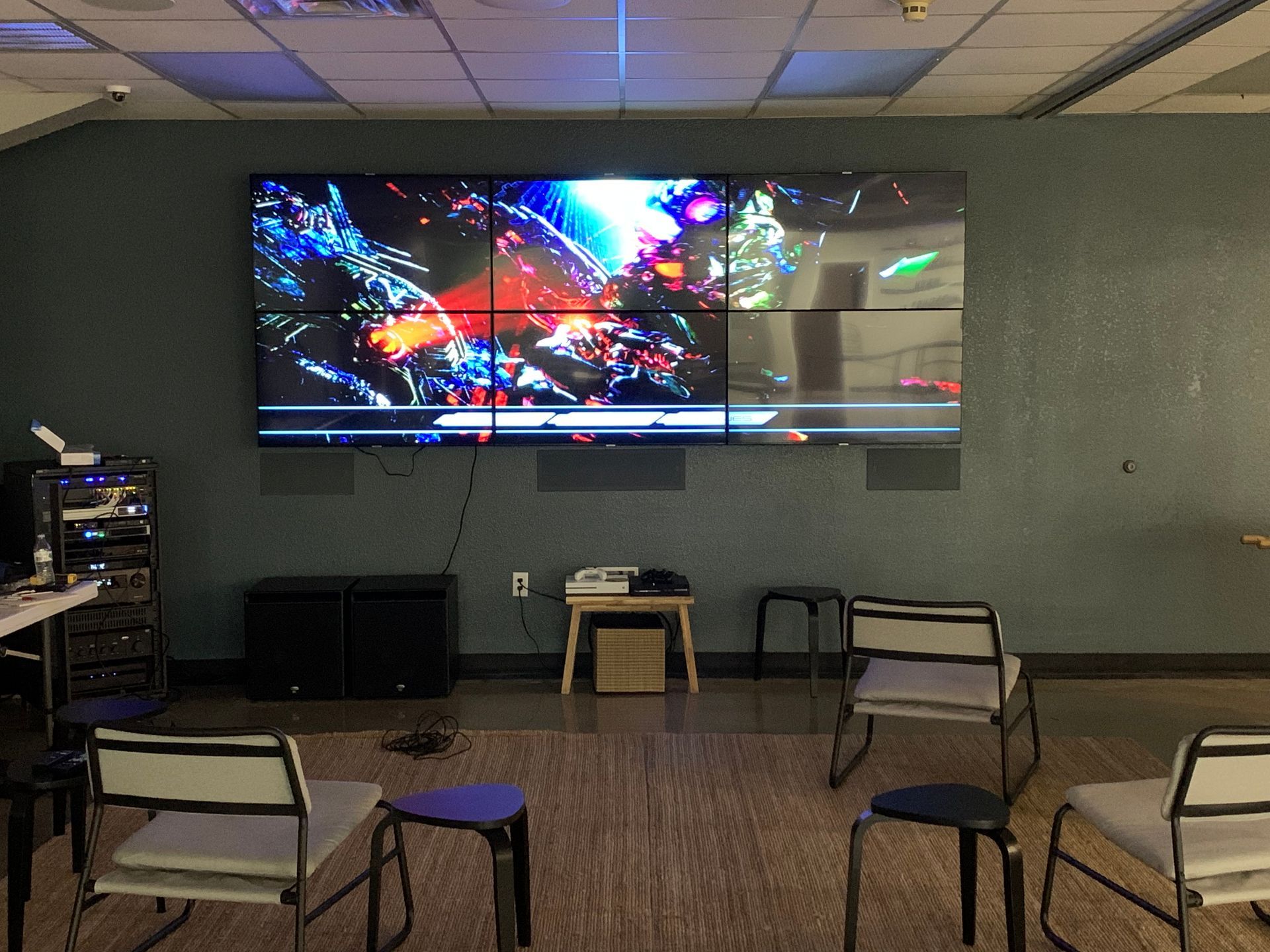 A room with chairs and a large screen on the wall