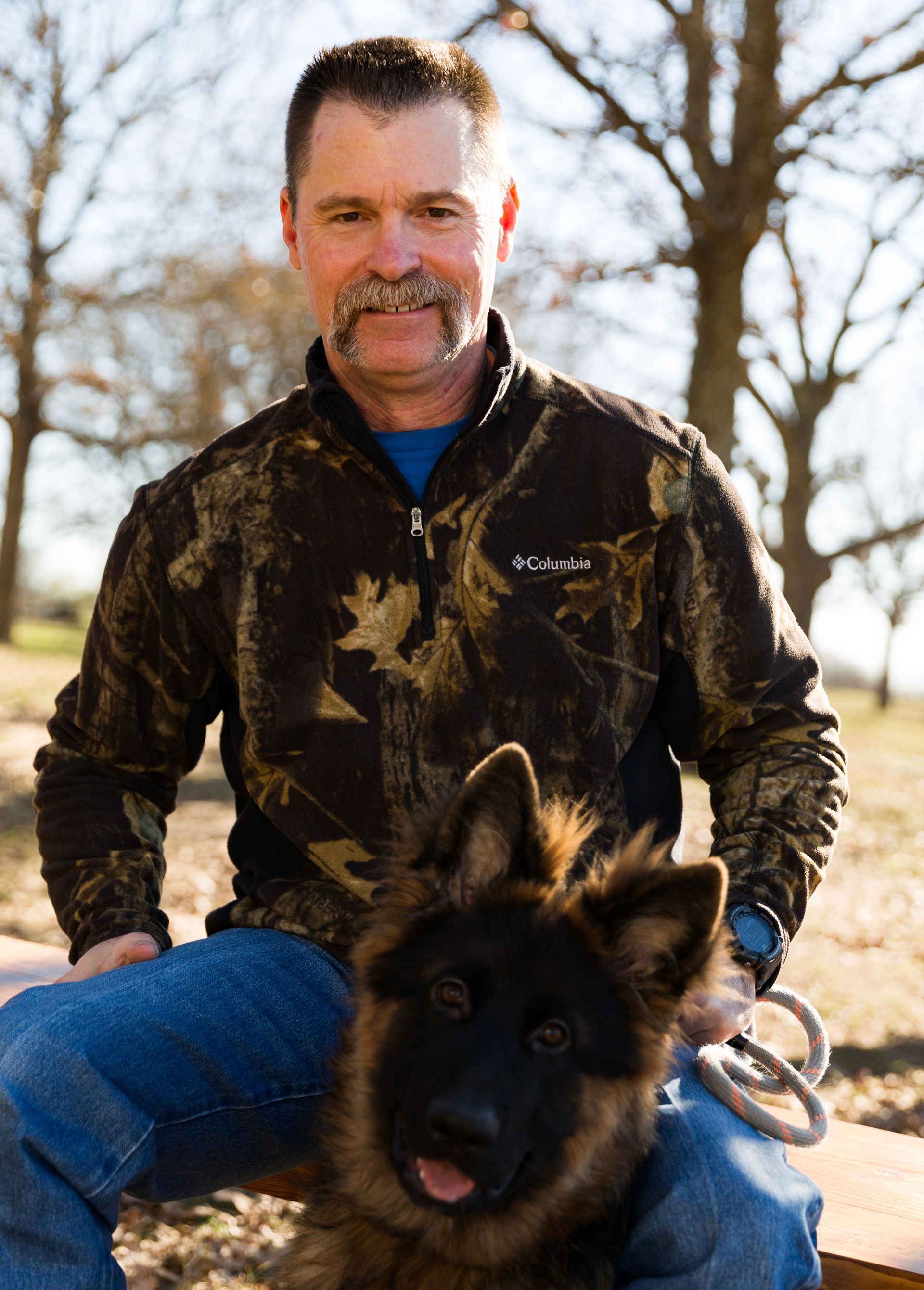 A man is sitting on a bench with a german shepherd dog