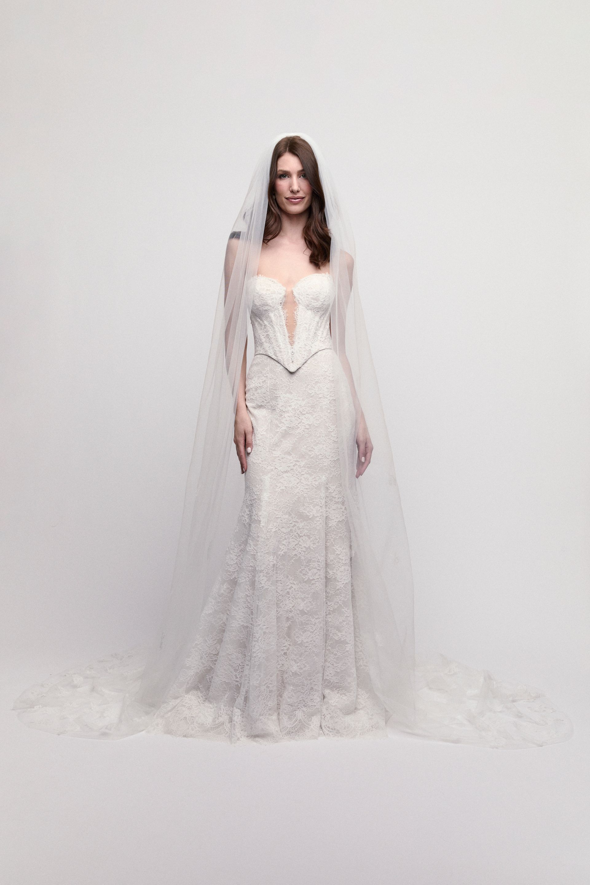 A woman in a white wedding dress is standing next to a fountain.