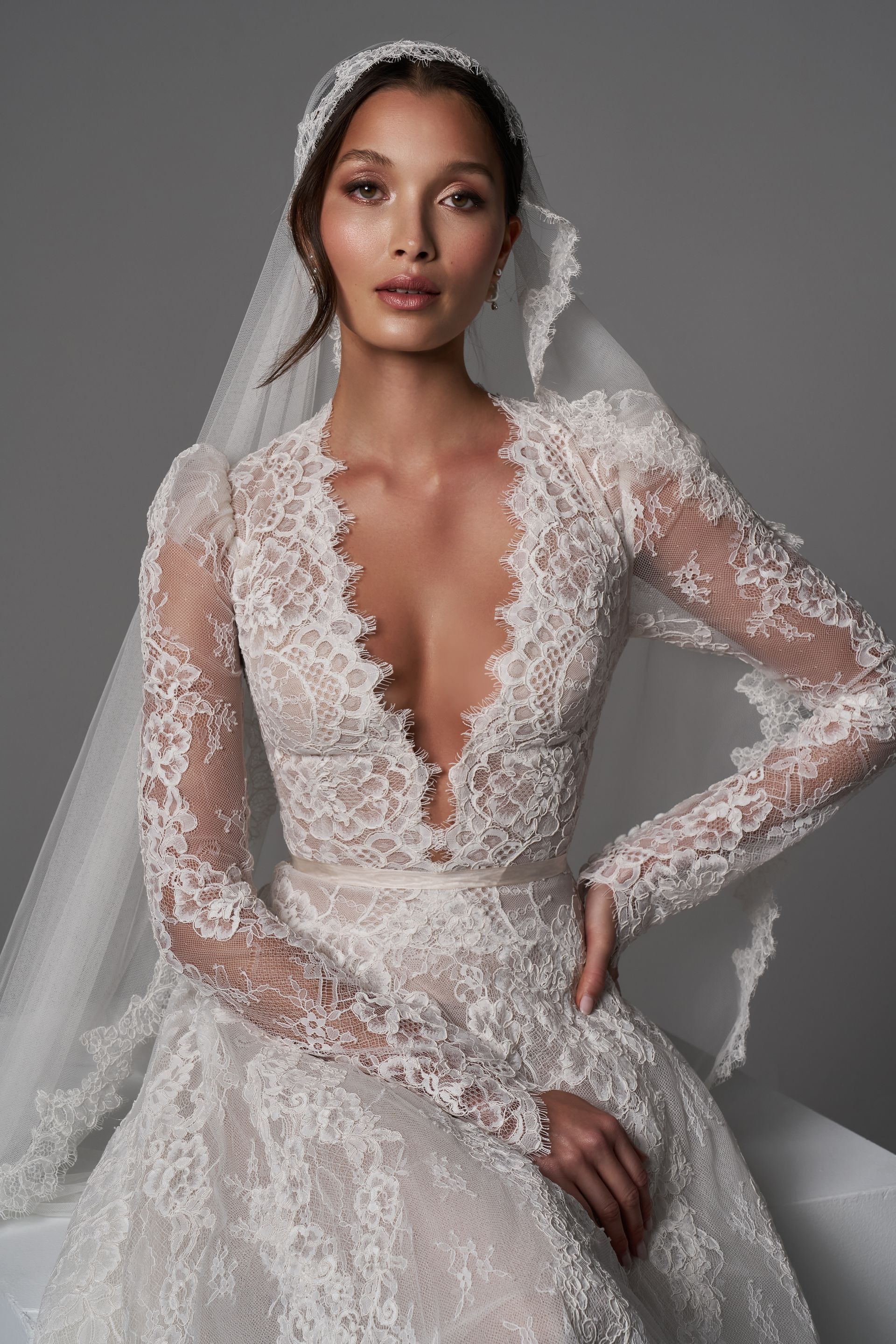 A woman in a wedding dress is standing in front of a stone wall.