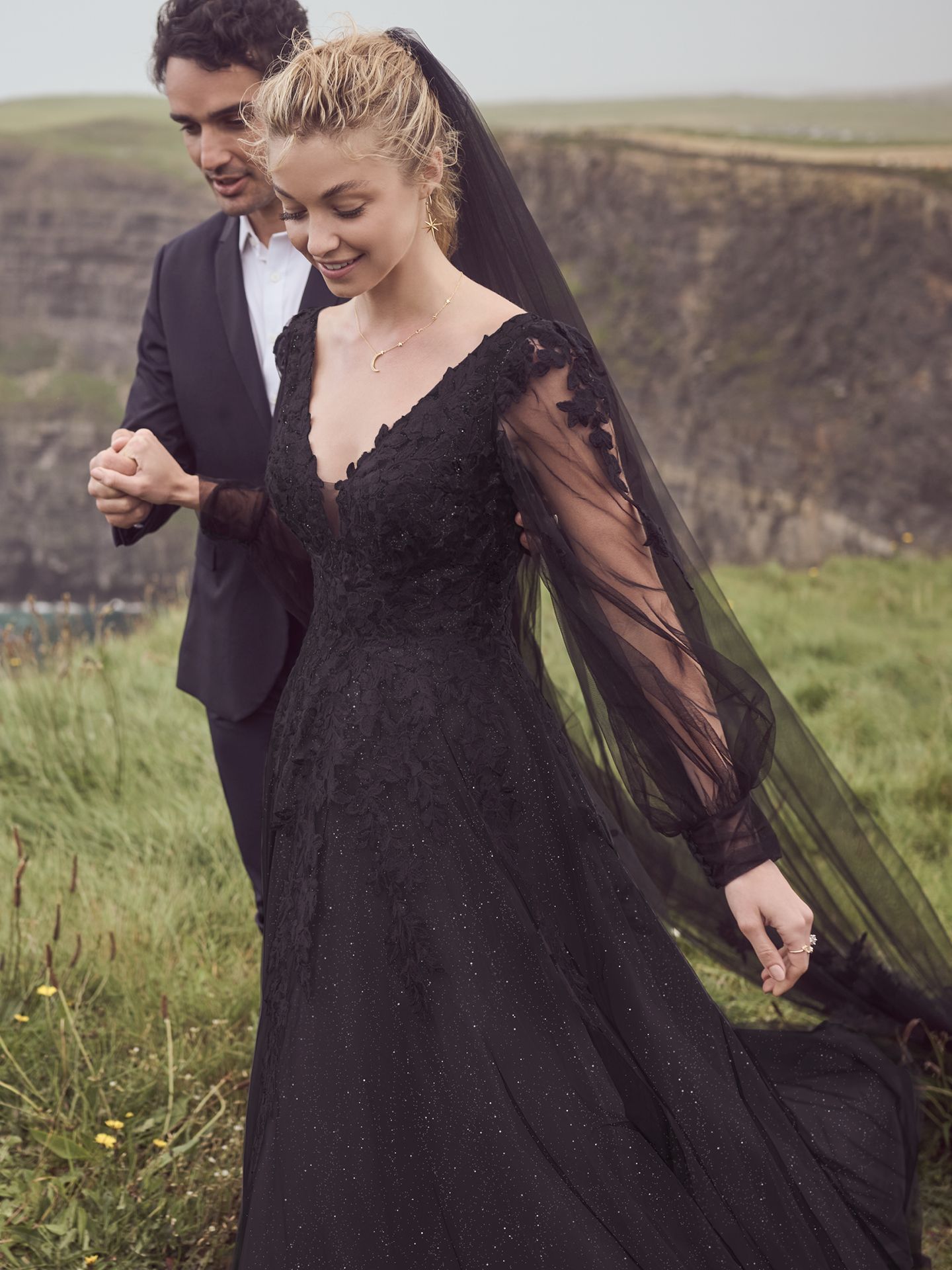 The bride is wearing a black dress and veil and the groom is wearing a black suit.
