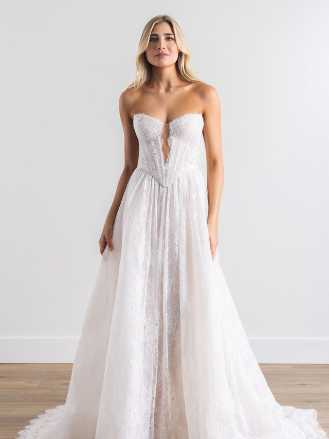 A woman in a wedding dress and veil is standing in front of a door.