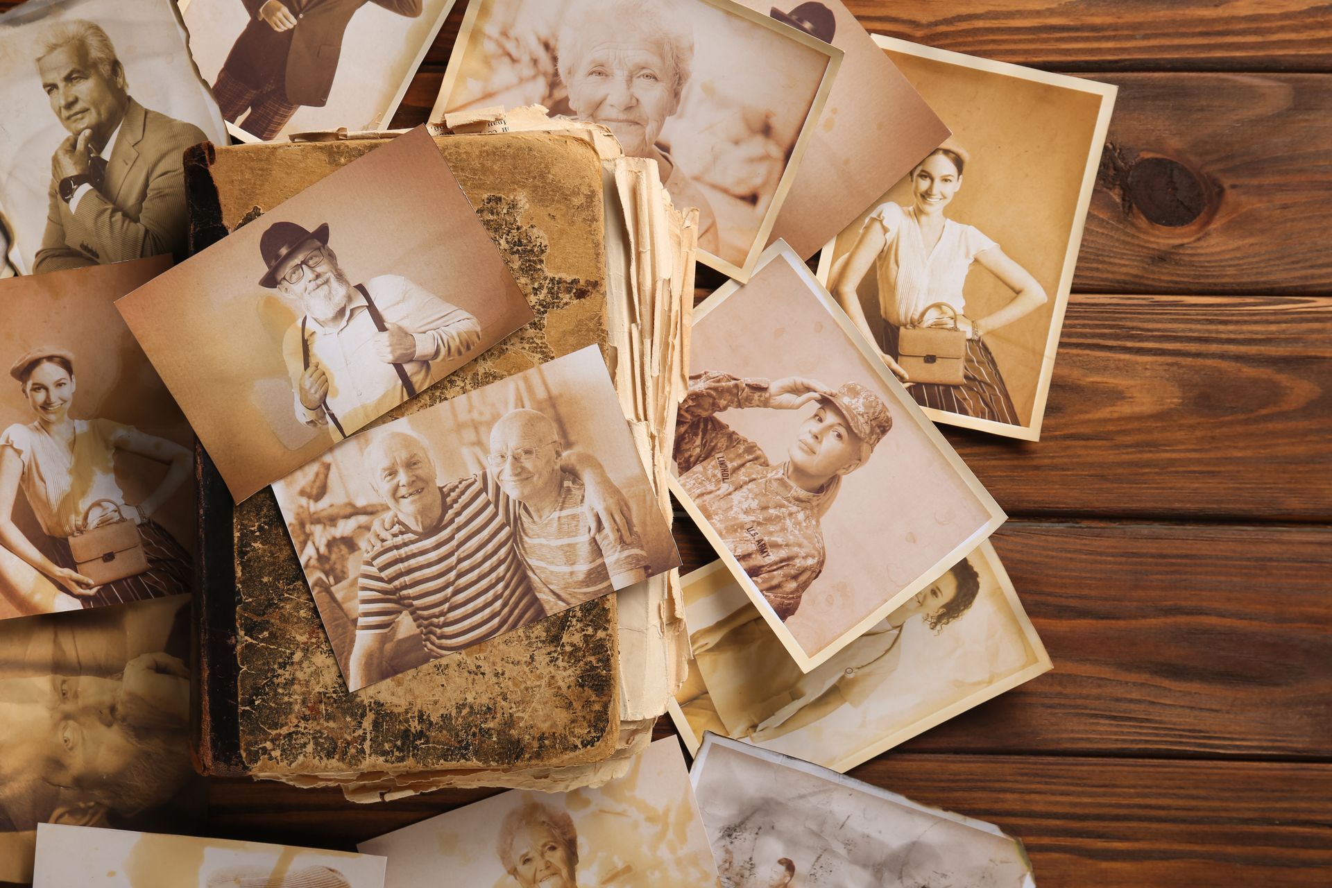Vintage sepia photos scattered on a wooden table, showing people in old-fashioned portraits and snapshots