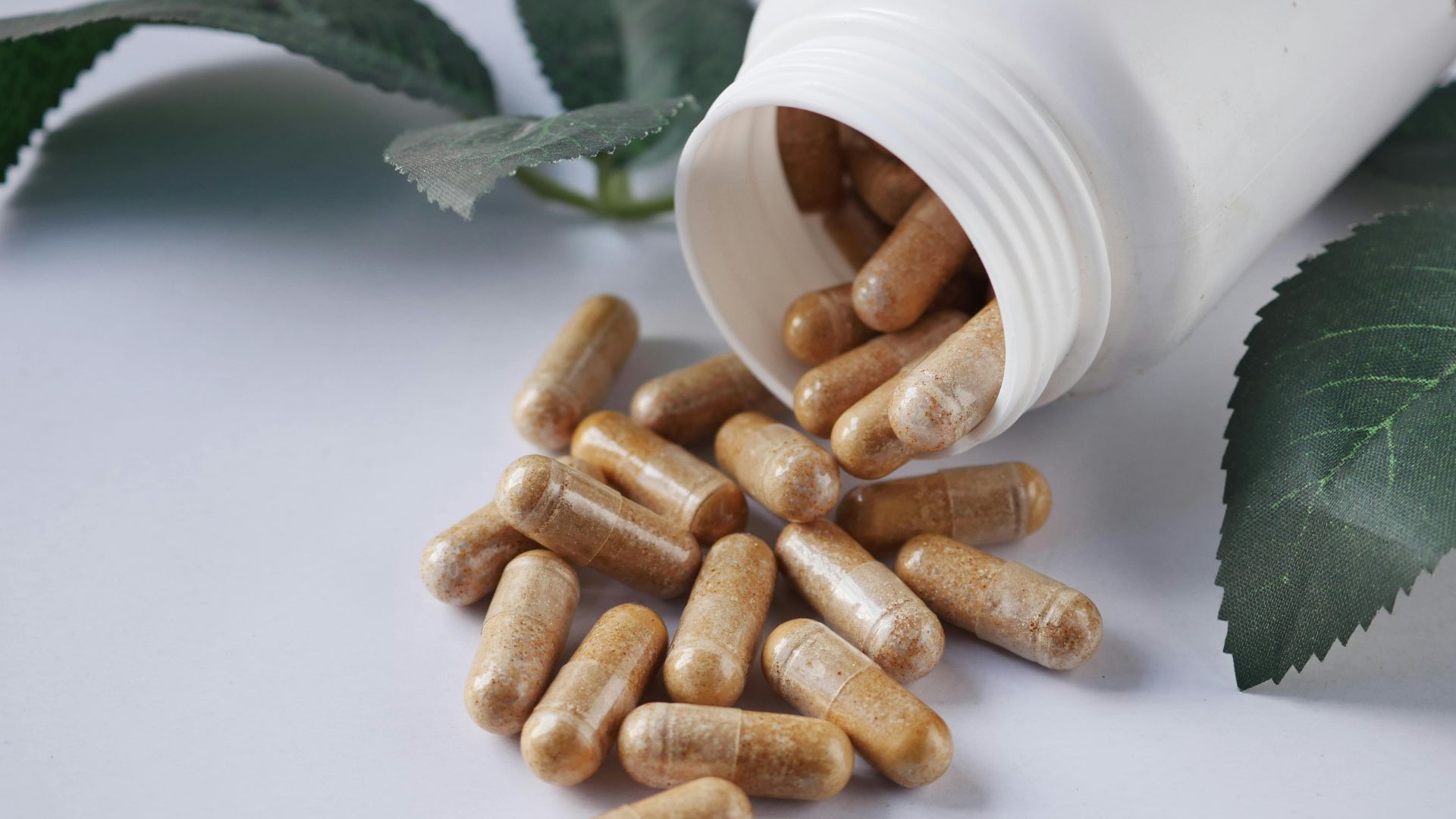 A bottle of pills is pouring out of it on a table.