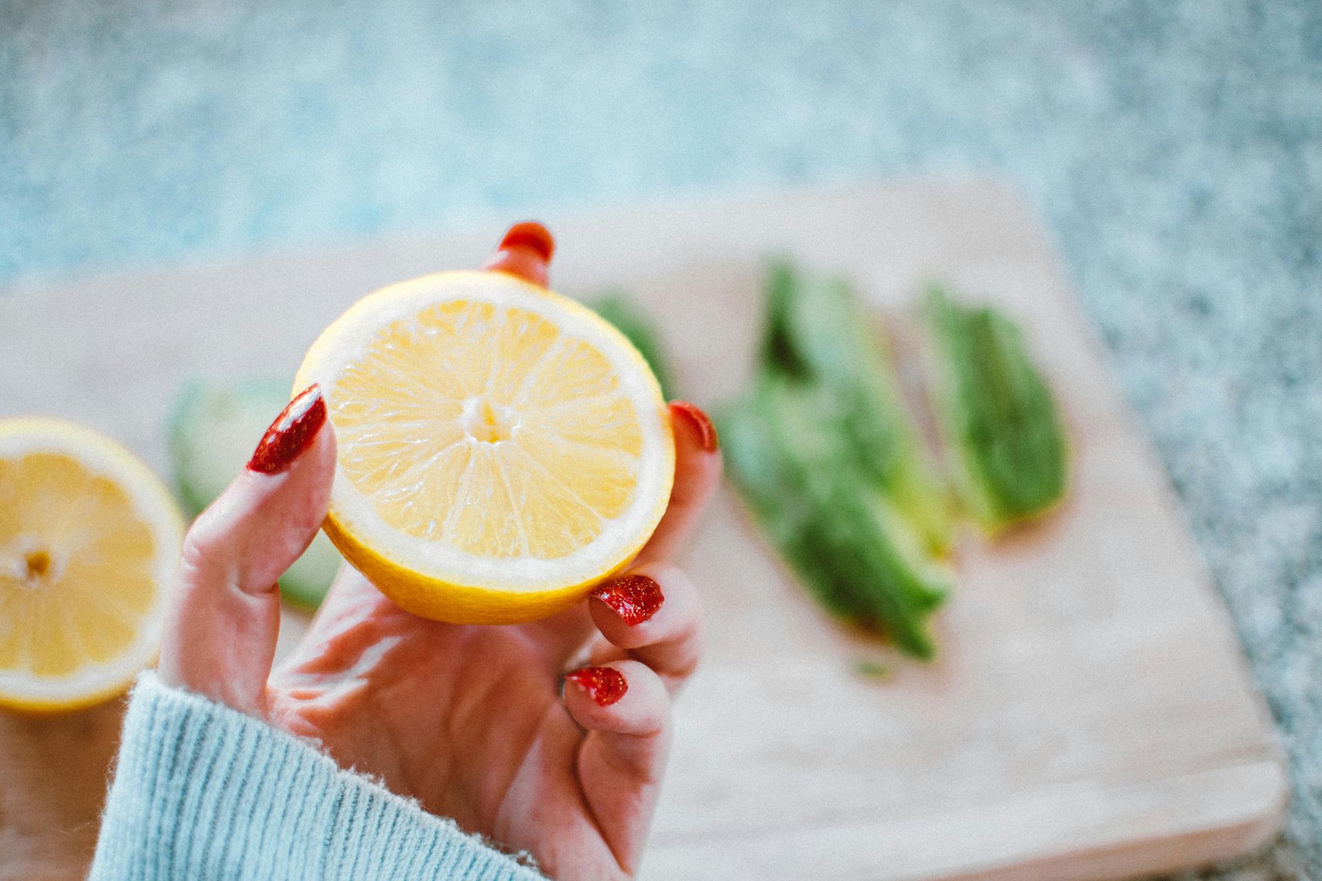 A woman is holding a slice of lemon in her hand.