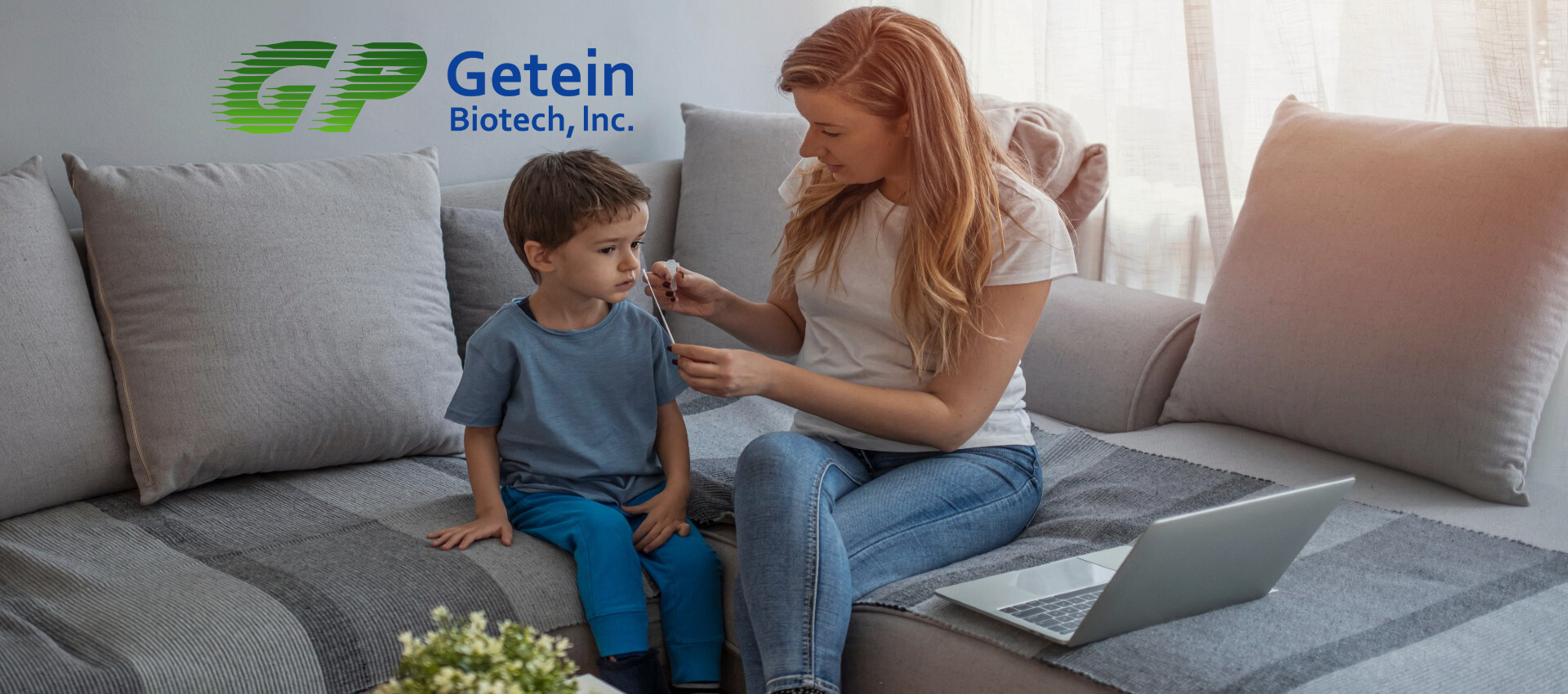 A woman is sitting on a couch with a child and a laptop.