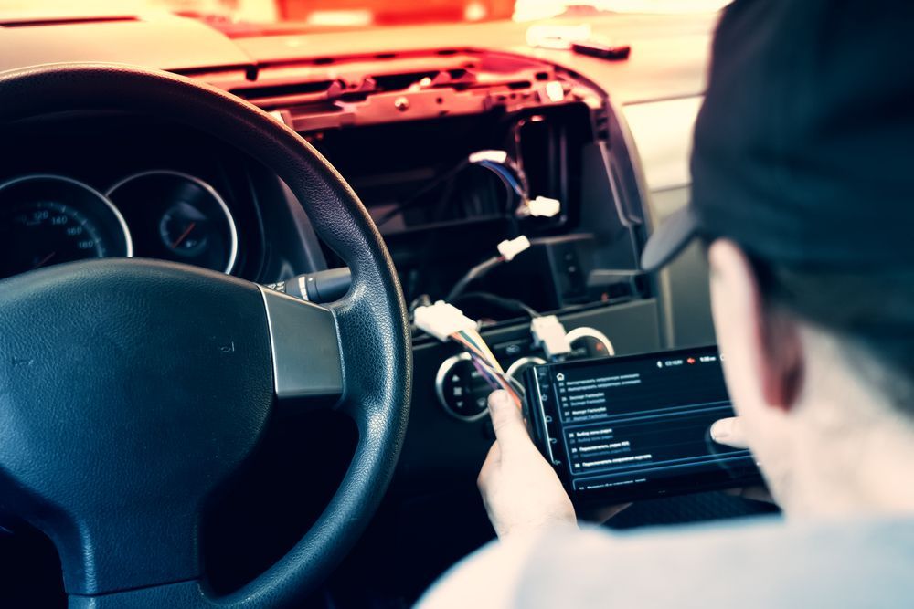 Persona che installa l'autoradio, cavi visibili, cruscotto aperto.