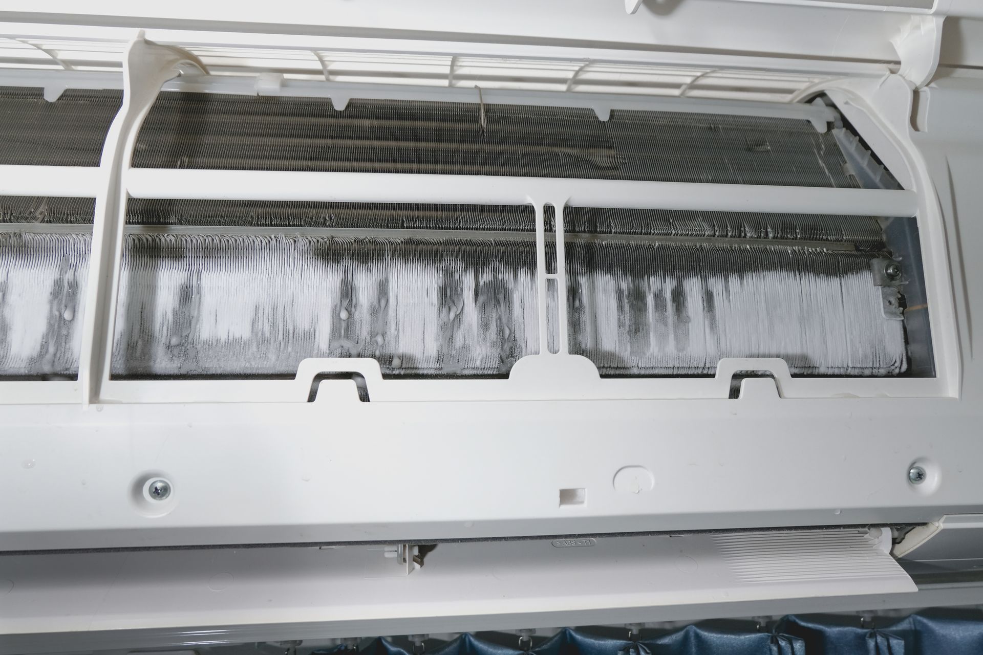 Air conditioner covered in ice buildup, indicating system malfunction on a warm summer day.