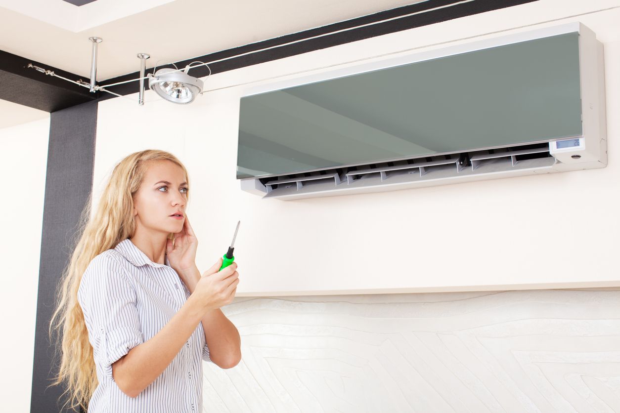 HVAC technician inspecting an air conditioner after diagnosing strange noises.