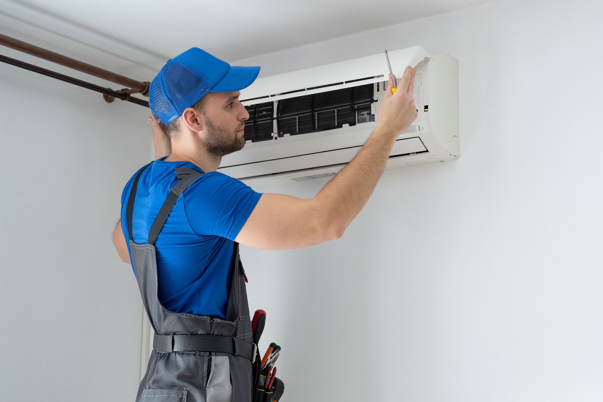 HVAC technician installing modern air conditioning system at home in Staten Island, New York.