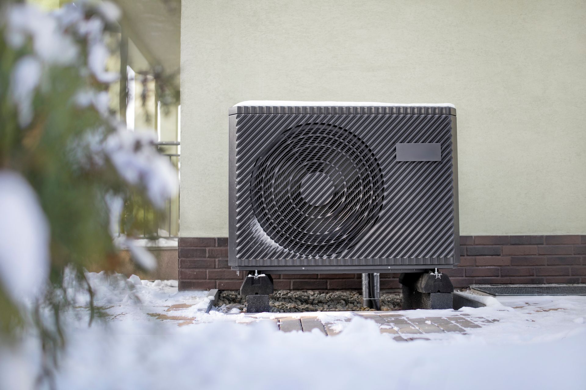 Heat pump outdoors in winter with cleared snow and proper airflow for reliable heating.