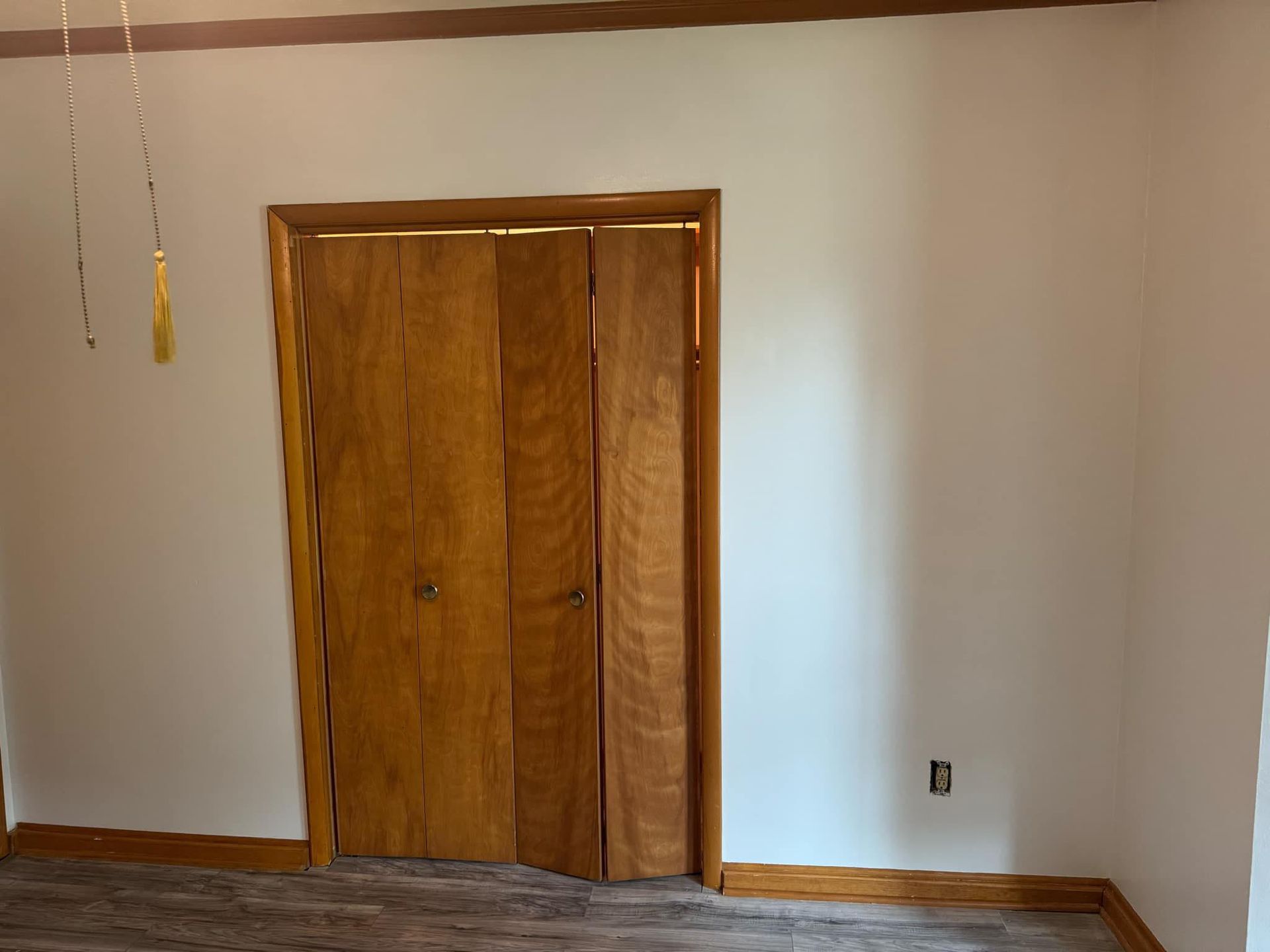 Wooden closet doors centered on white walls, wooden trim on floor and around the door.