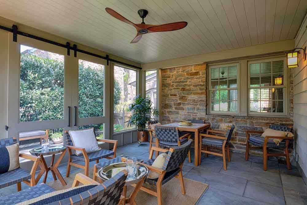 The front porch of a house with a wooden door and a white railing.