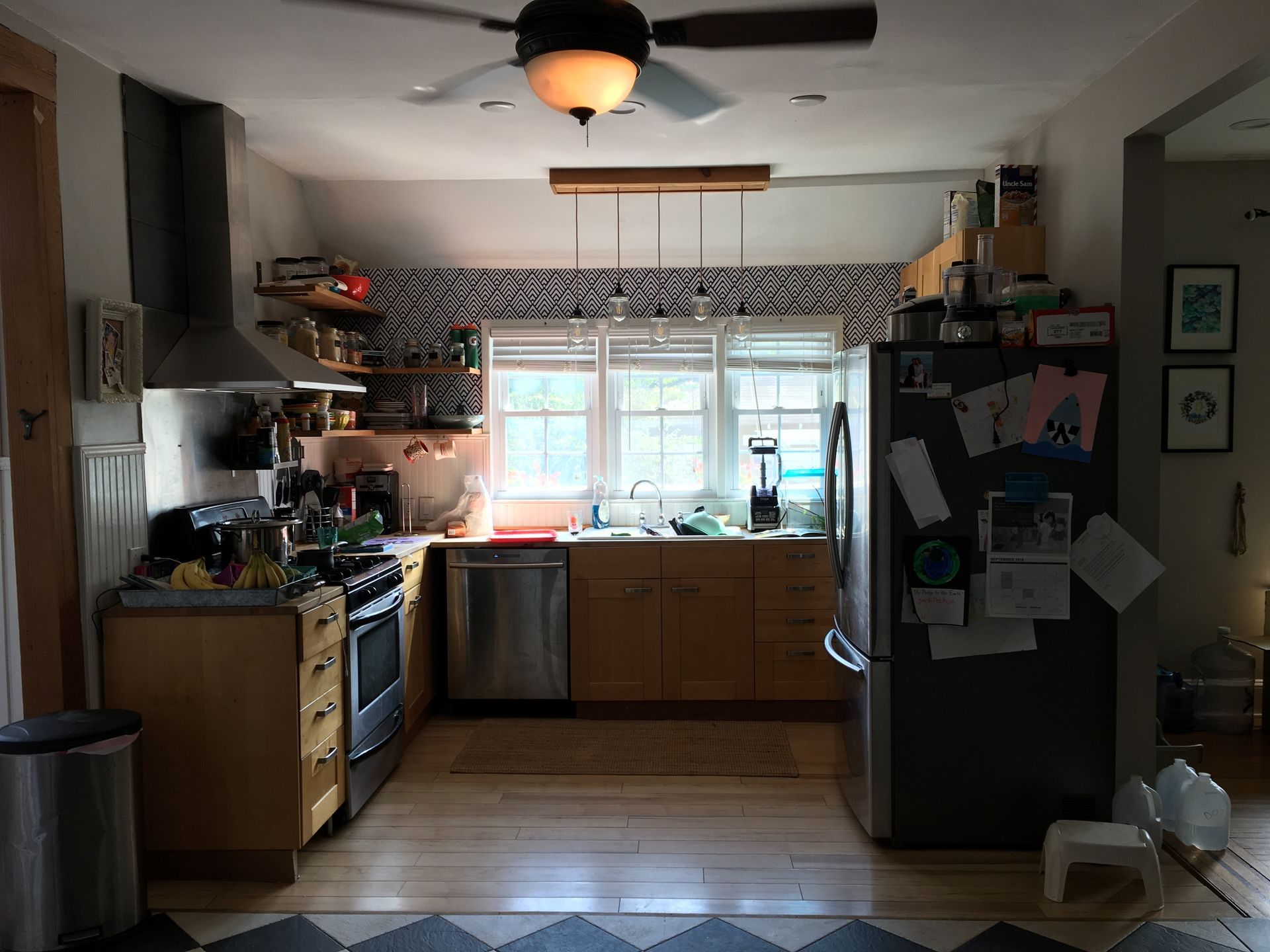 A kitchen with a stove a refrigerator and a ceiling fan.