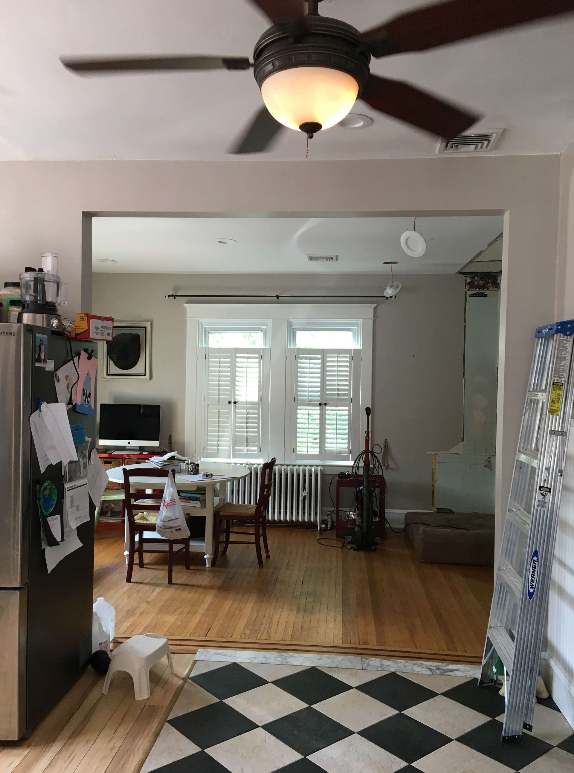 A living room with a ceiling fan and a checkered rug.