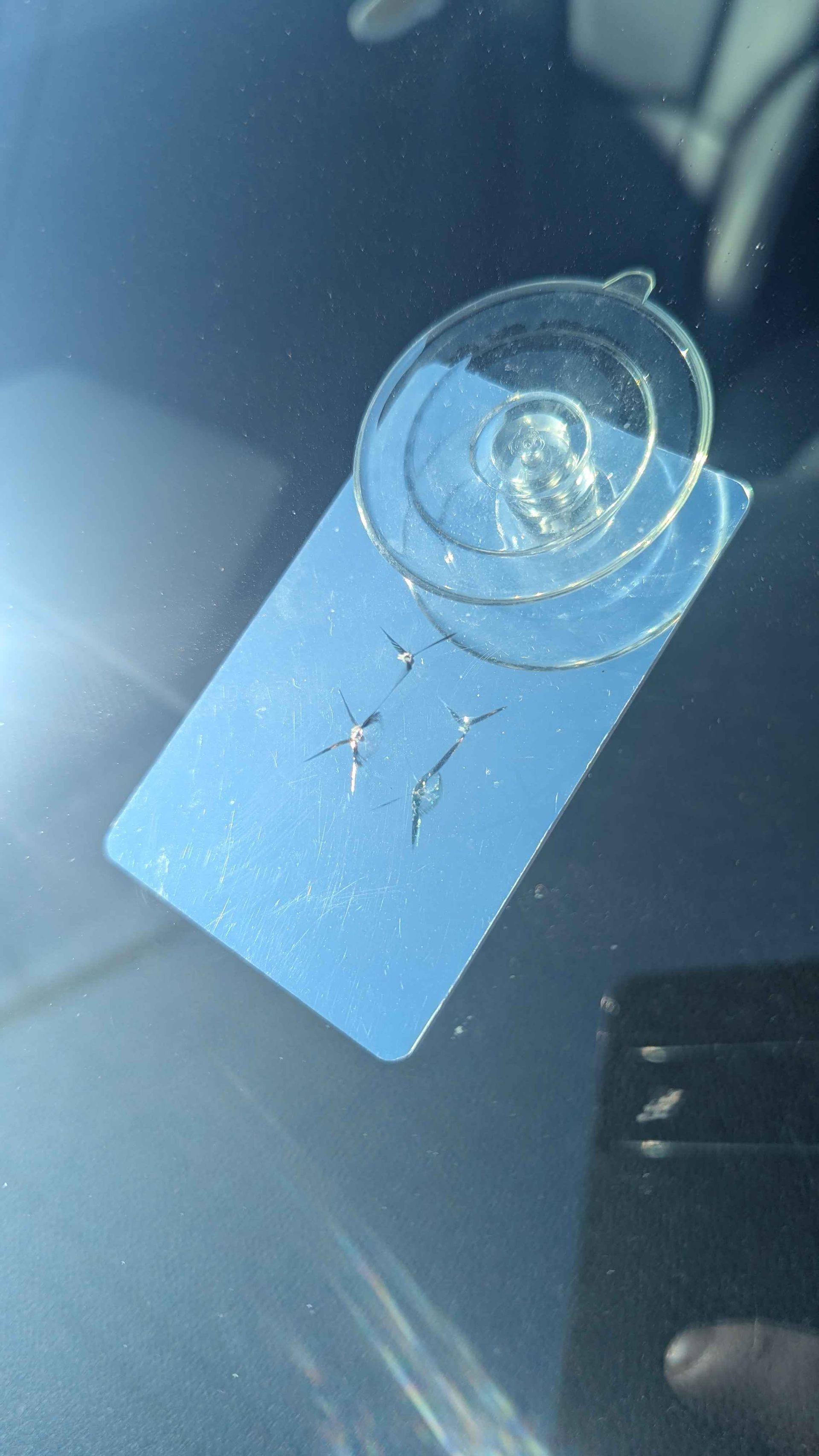 Windshield with a crack, covered by a blue card and a suction cup.