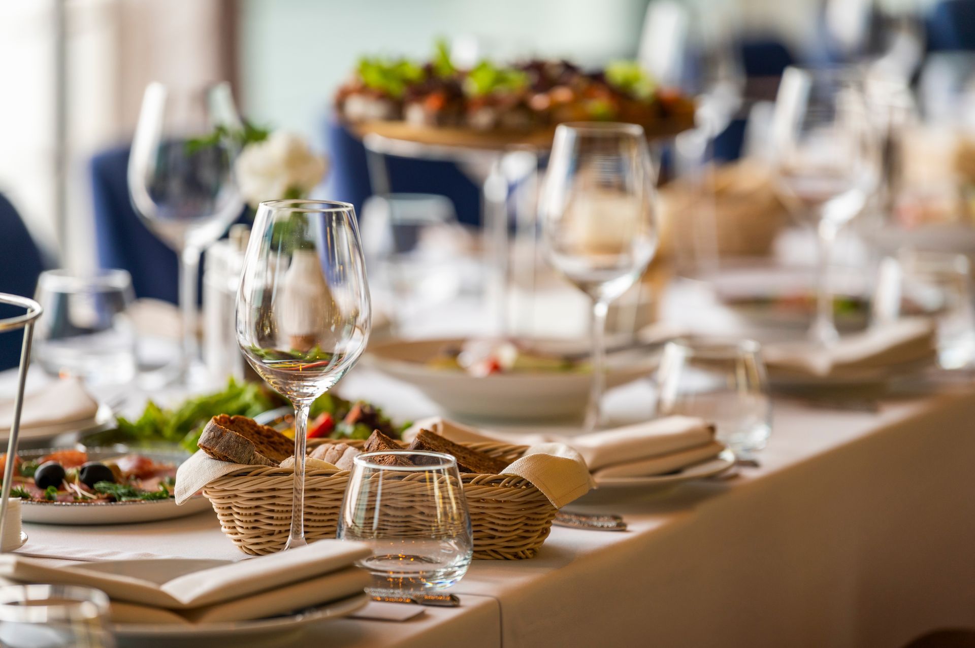 Elegant restaurant table setting with wine glasses, food, and linen napkins.
