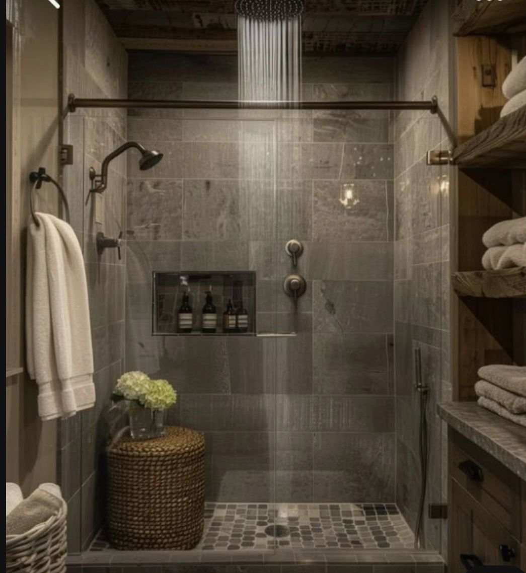 Rustic shower with gray tile, glass door, rain showerhead, and wooden shelves.