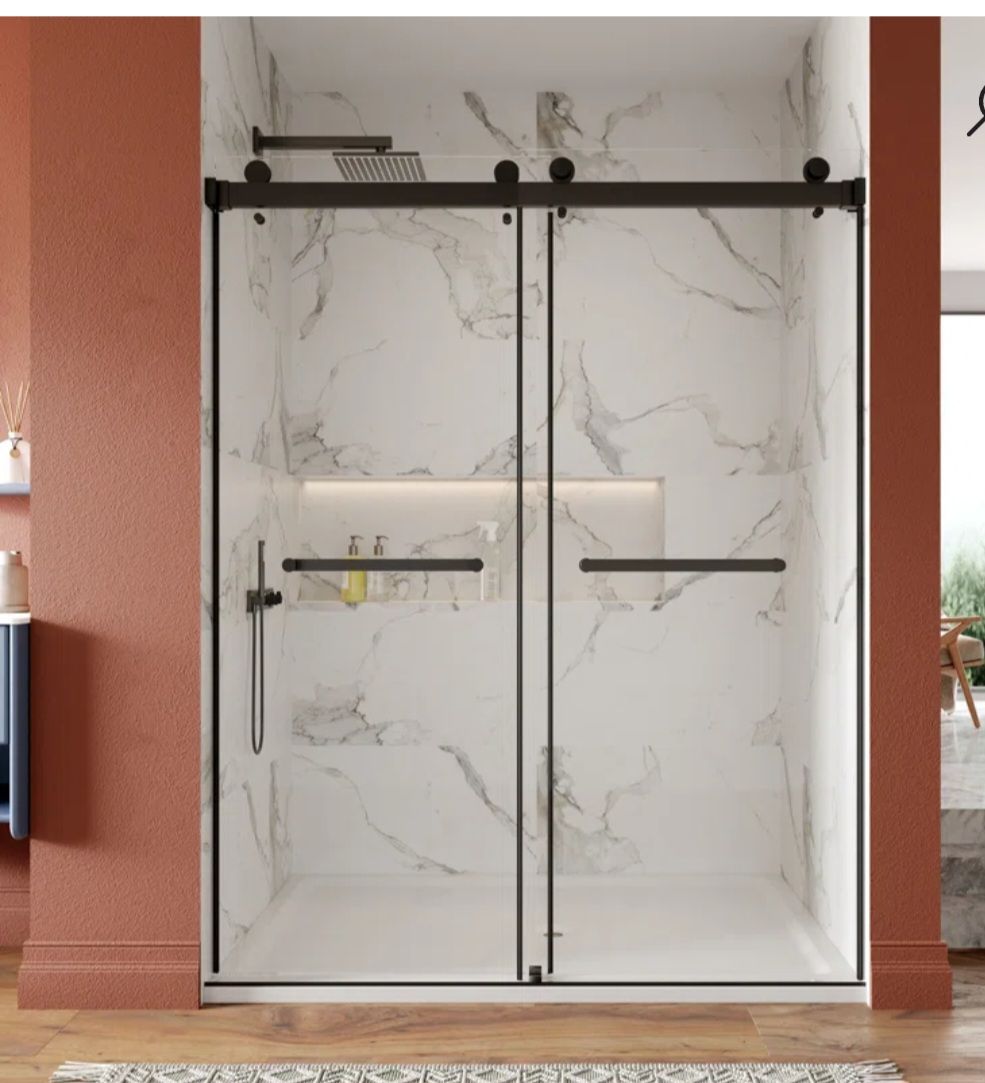 Black framed sliding shower doors with marble-patterned walls and dark fixtures.