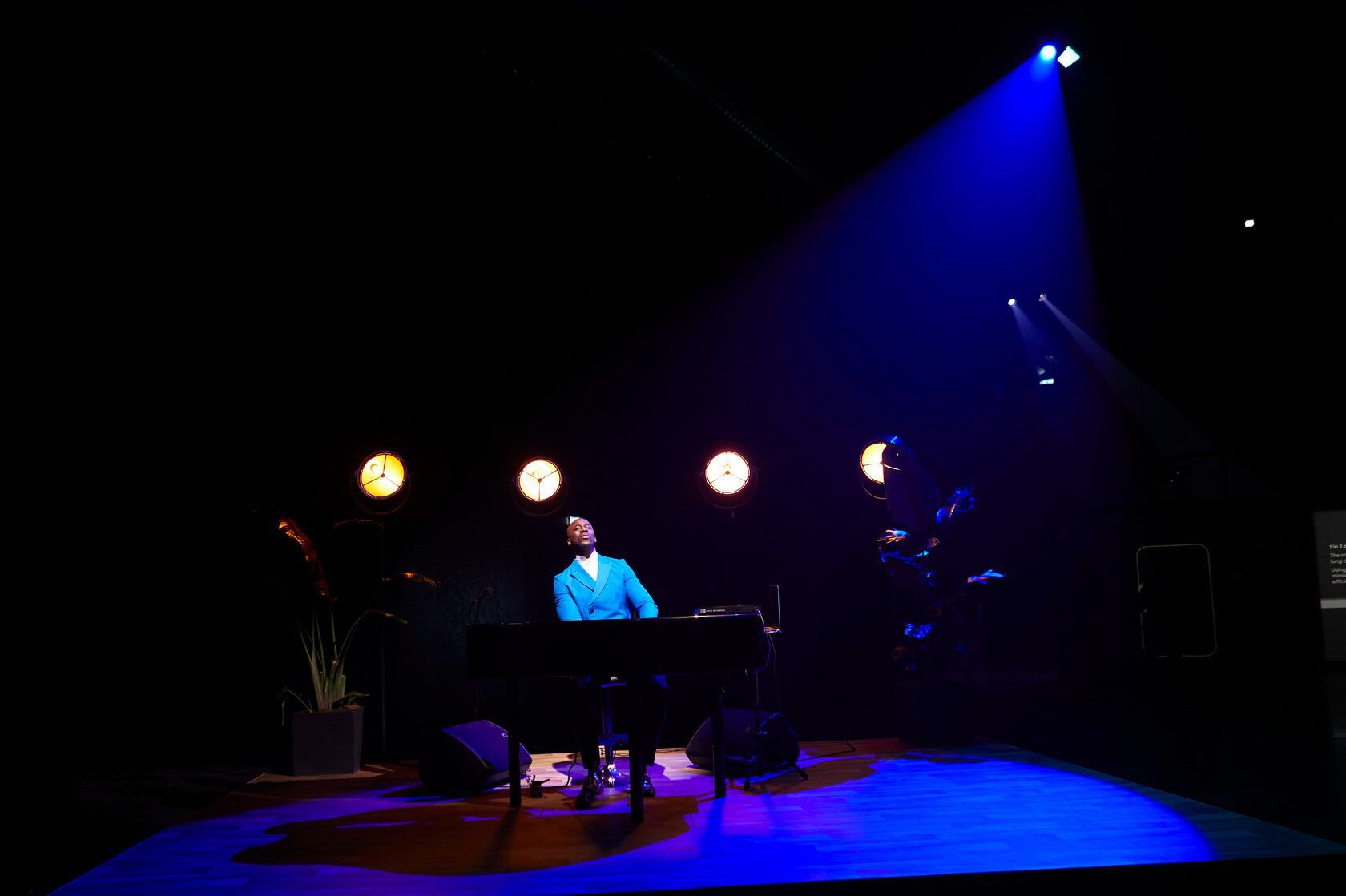 Pianist illuminated on a dark stage by a spotlight and stage lights.