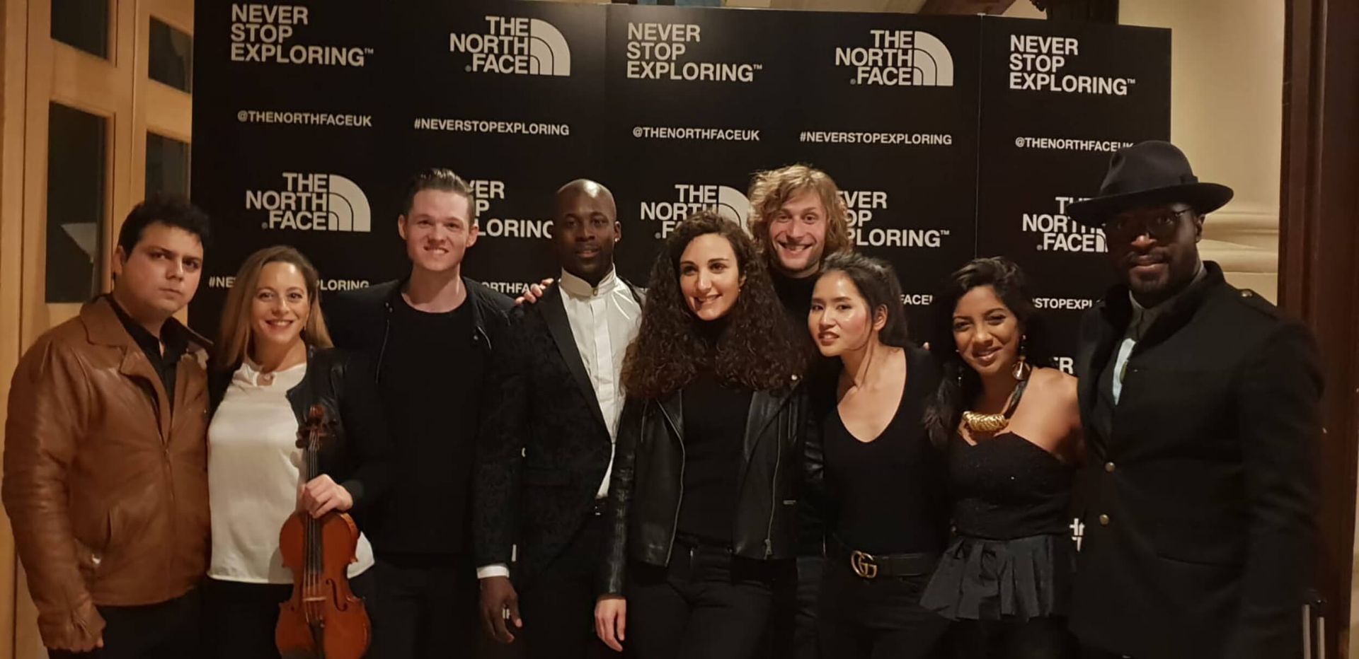 Group of people posing for a photo in front of a The North Face backdrop.