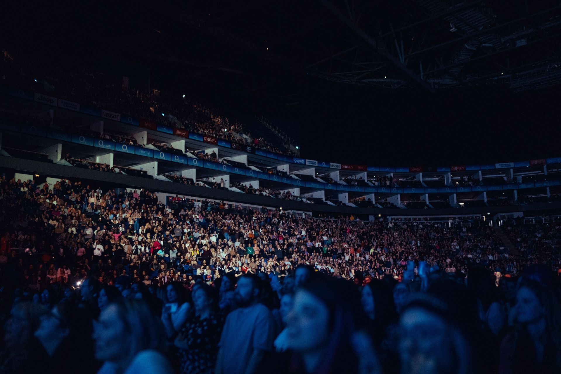Large crowd at a night concert in a stadium with lit stages and tiers of people.