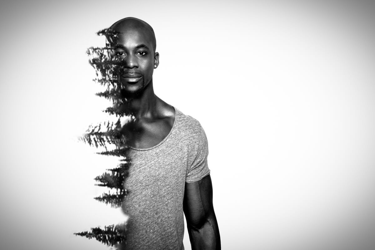 Black and white portrait of a man with a tree overlay on the left side of his body.