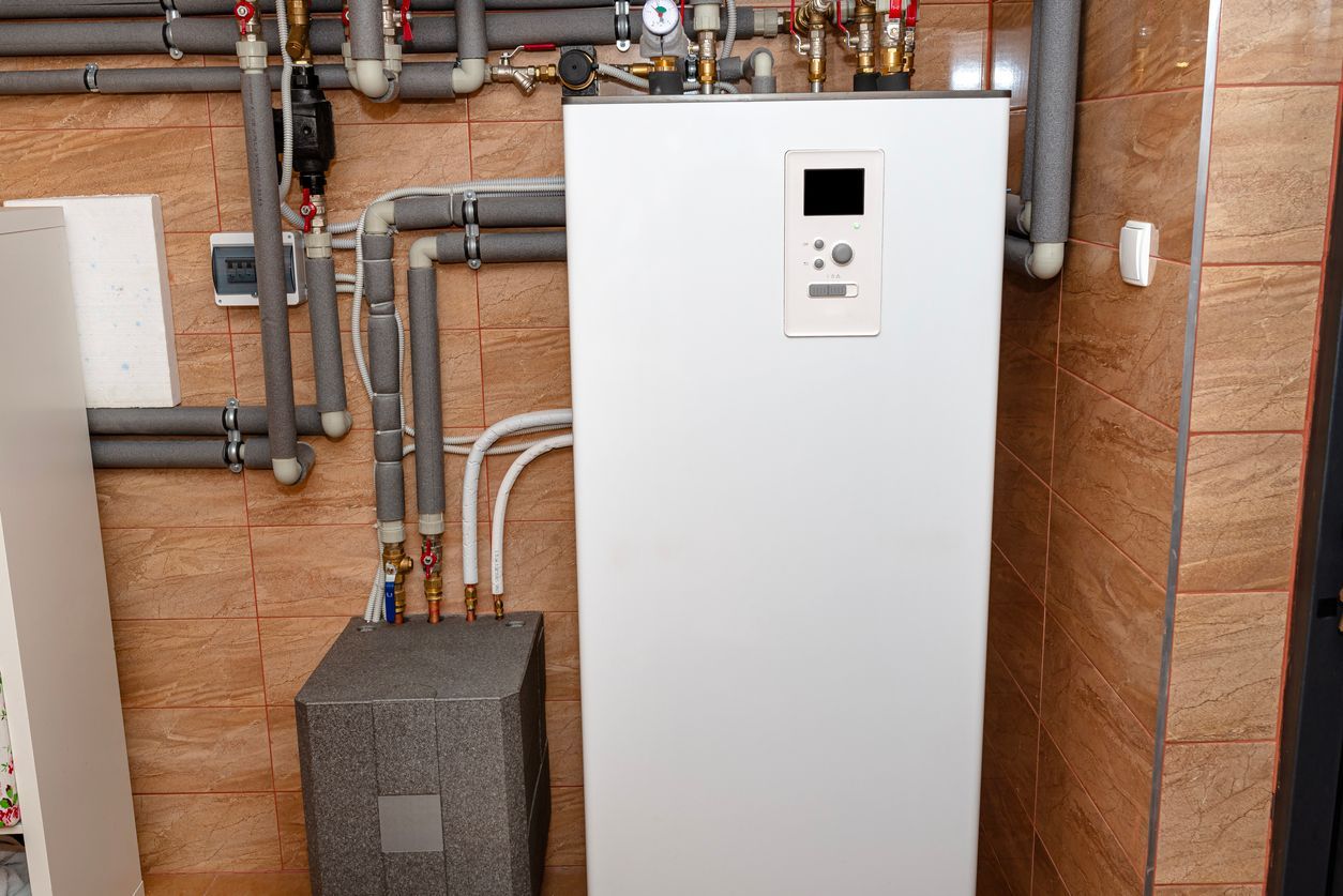Upgraded white heat pump system with connected pipes on tiled wall installed by Airmax.