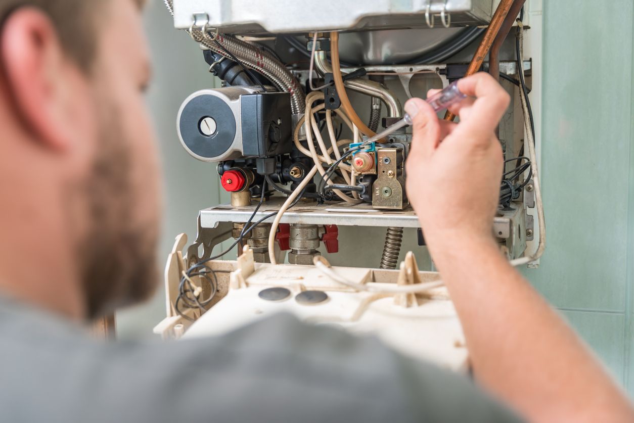 Airmax technician repairing a broken furnace during winter with a screwdriver in a utility room.