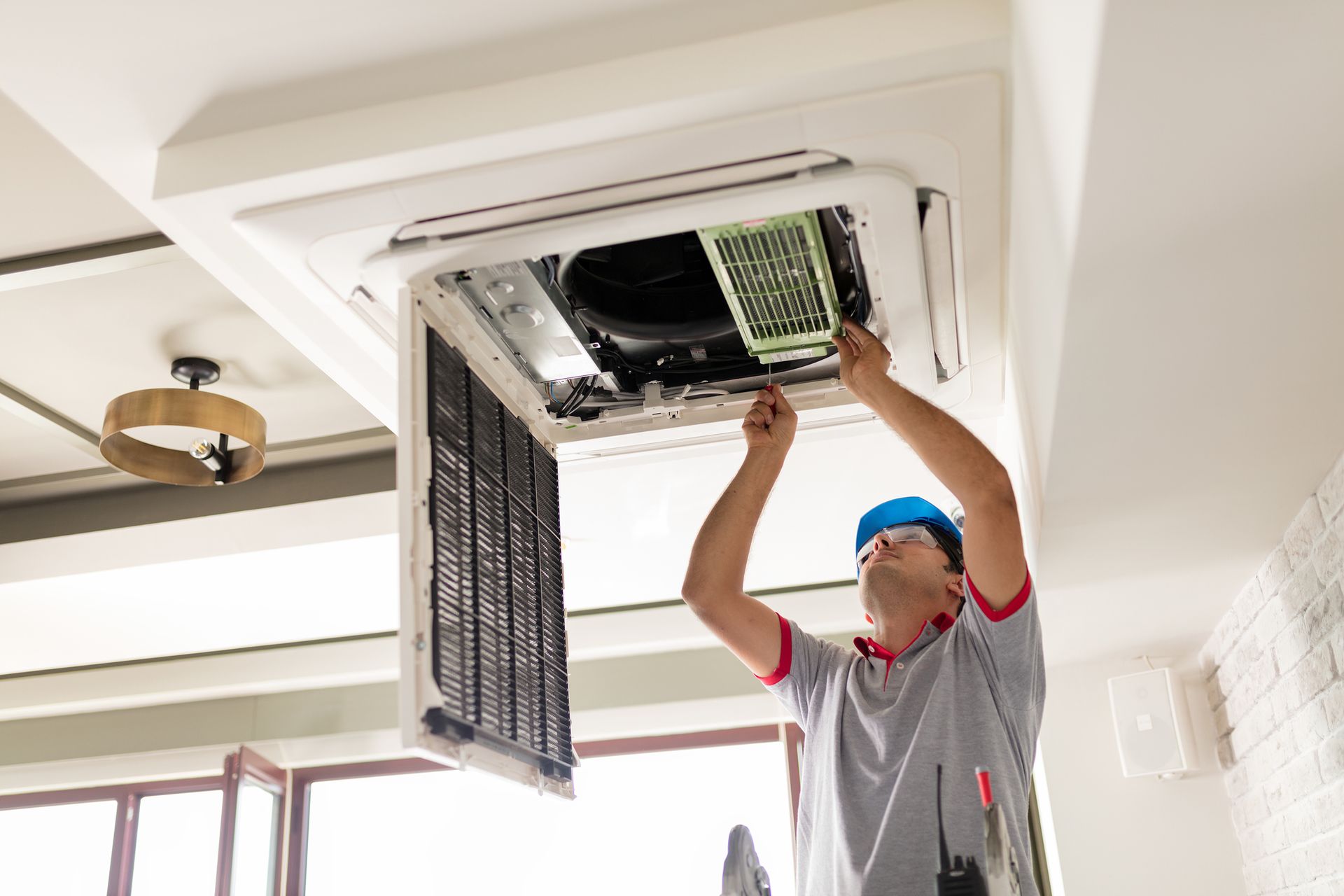 Airmax technician repairing a commercial ceiling air conditioner unit with the access panel open.
