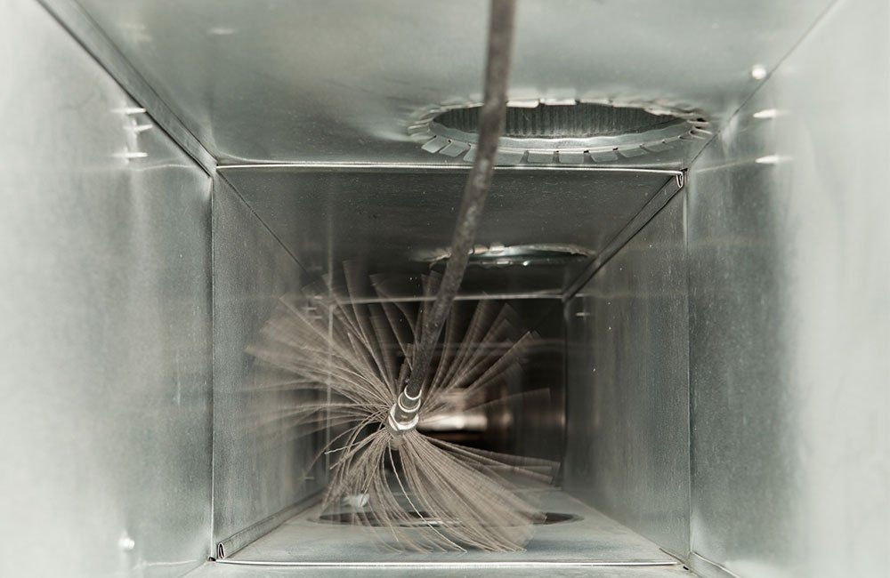 Brush cleaning an air duct, removing dust.