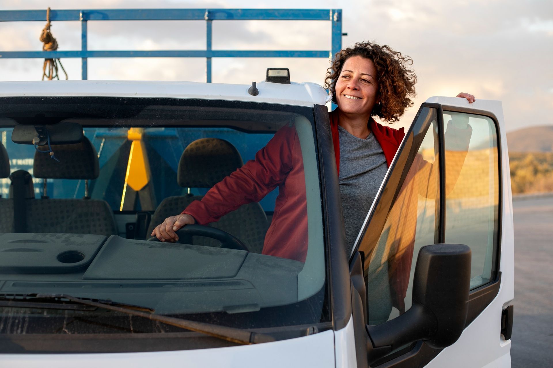 A woman is sitting in the driver's seat of a white truck.