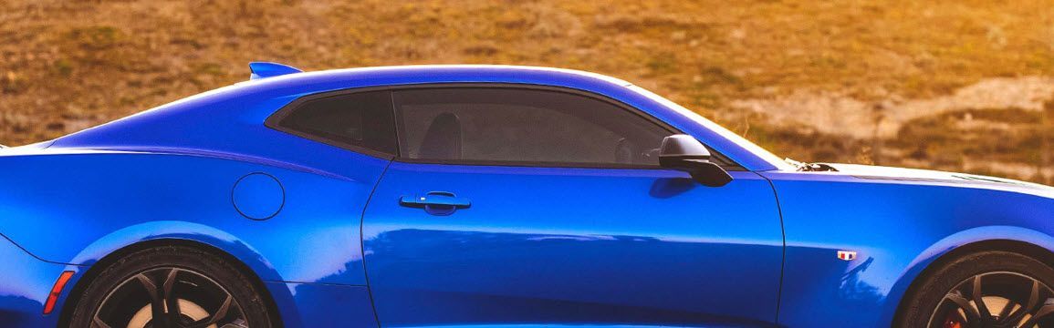 A blue sports car is parked on the side of the road.