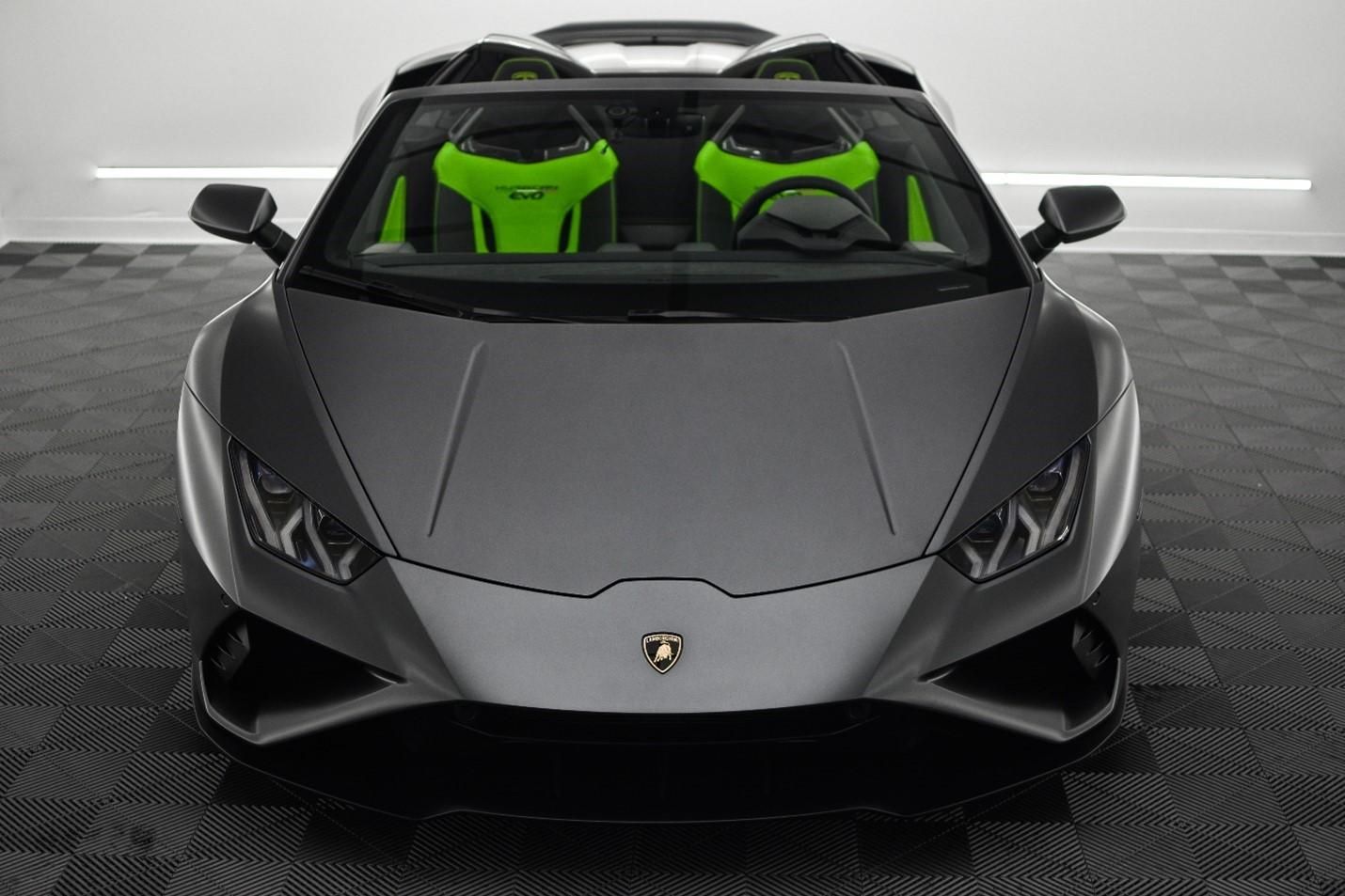 A gray lamborghini with green seats is parked in a garage.