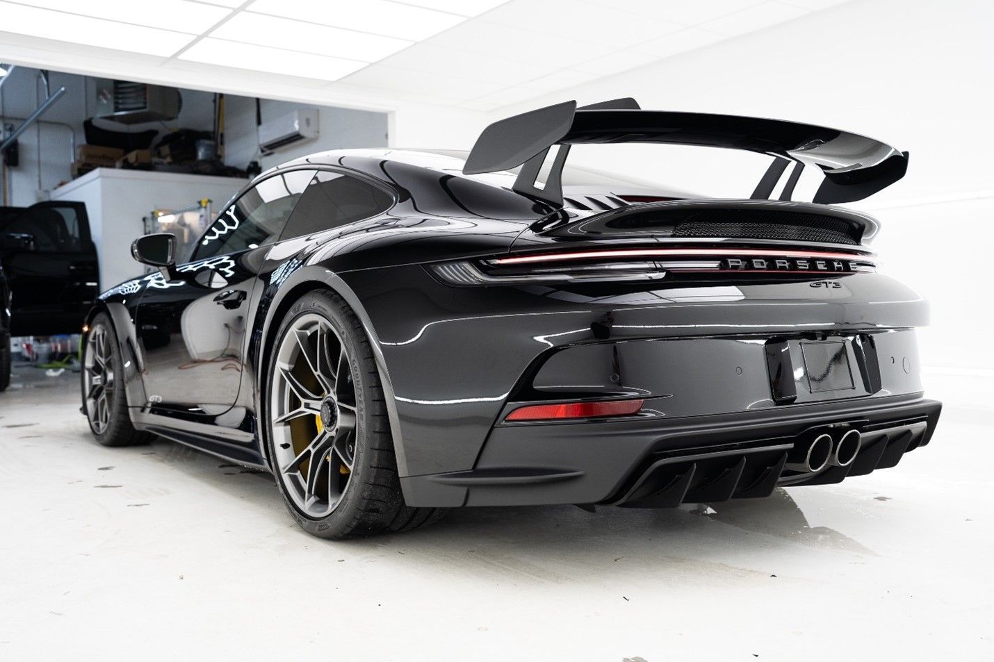 A black porsche 911 gt3 rs is parked in a garage.