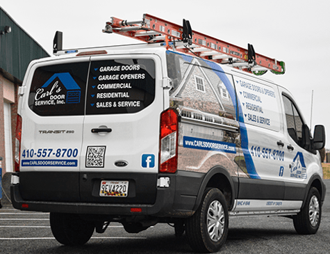 A white van with a ladder on top of it is parked in a parking lot.