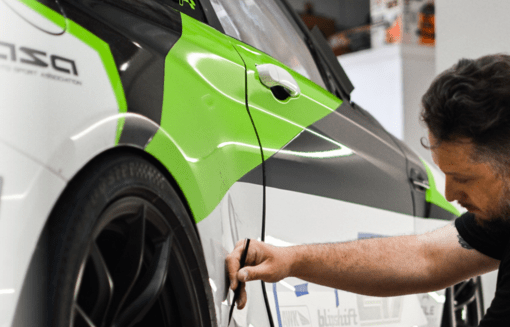 A man is working on a green and white car.