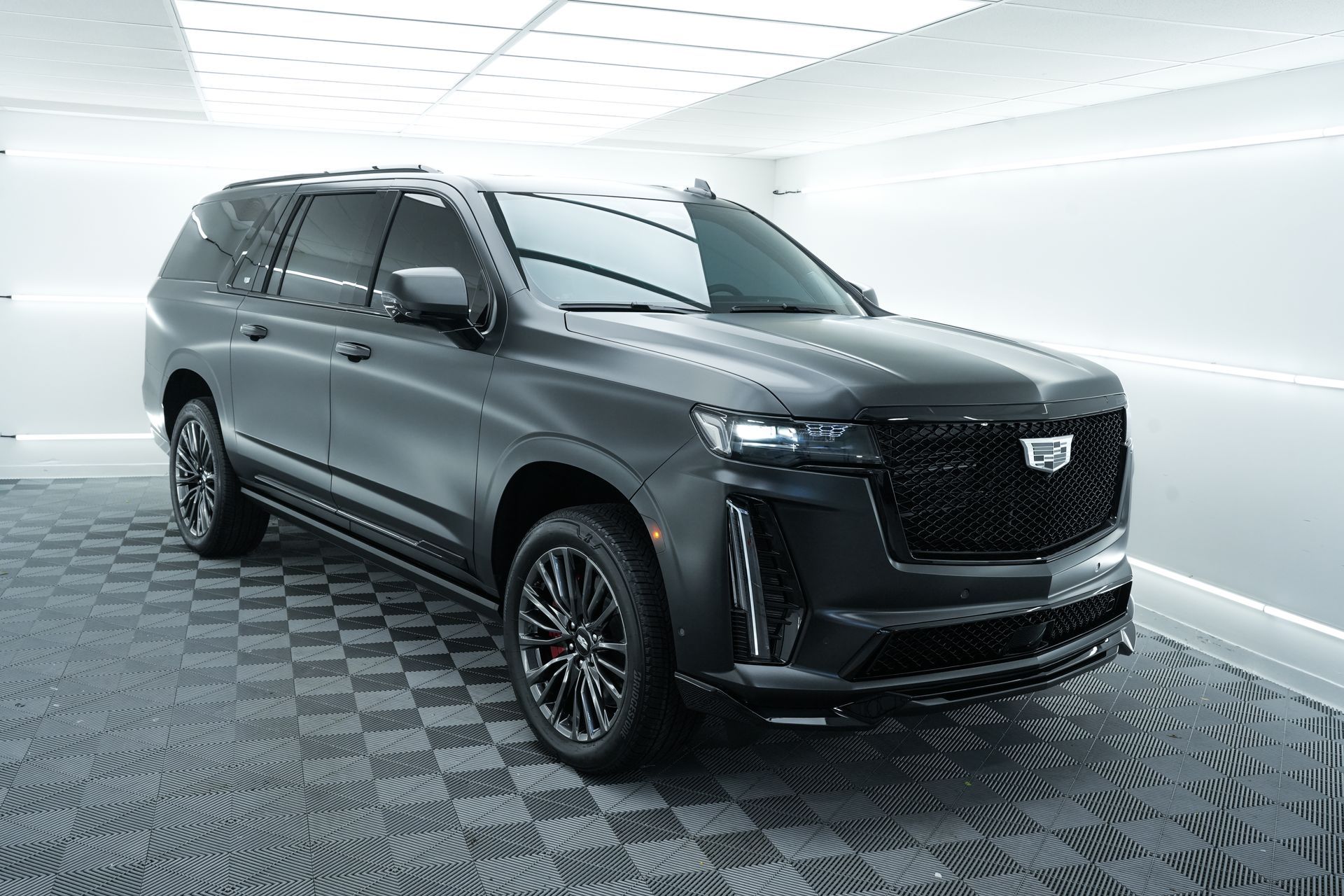 A black cadillac escalade is parked in a garage.