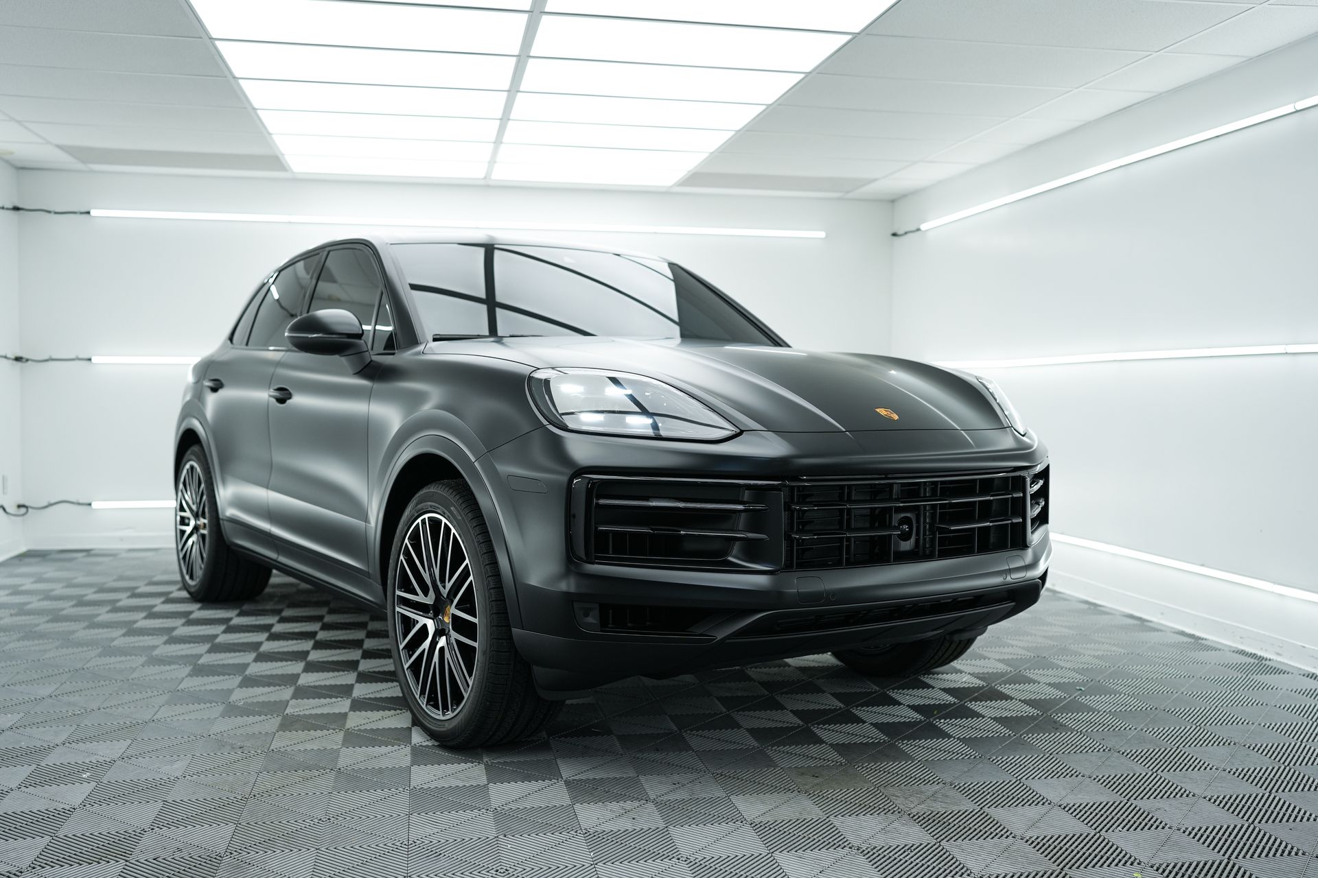 A black porsche cayenne is parked in a garage.