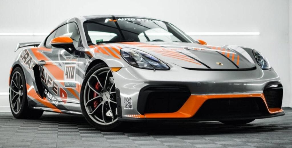 A silver and orange sports car is parked in a garage.