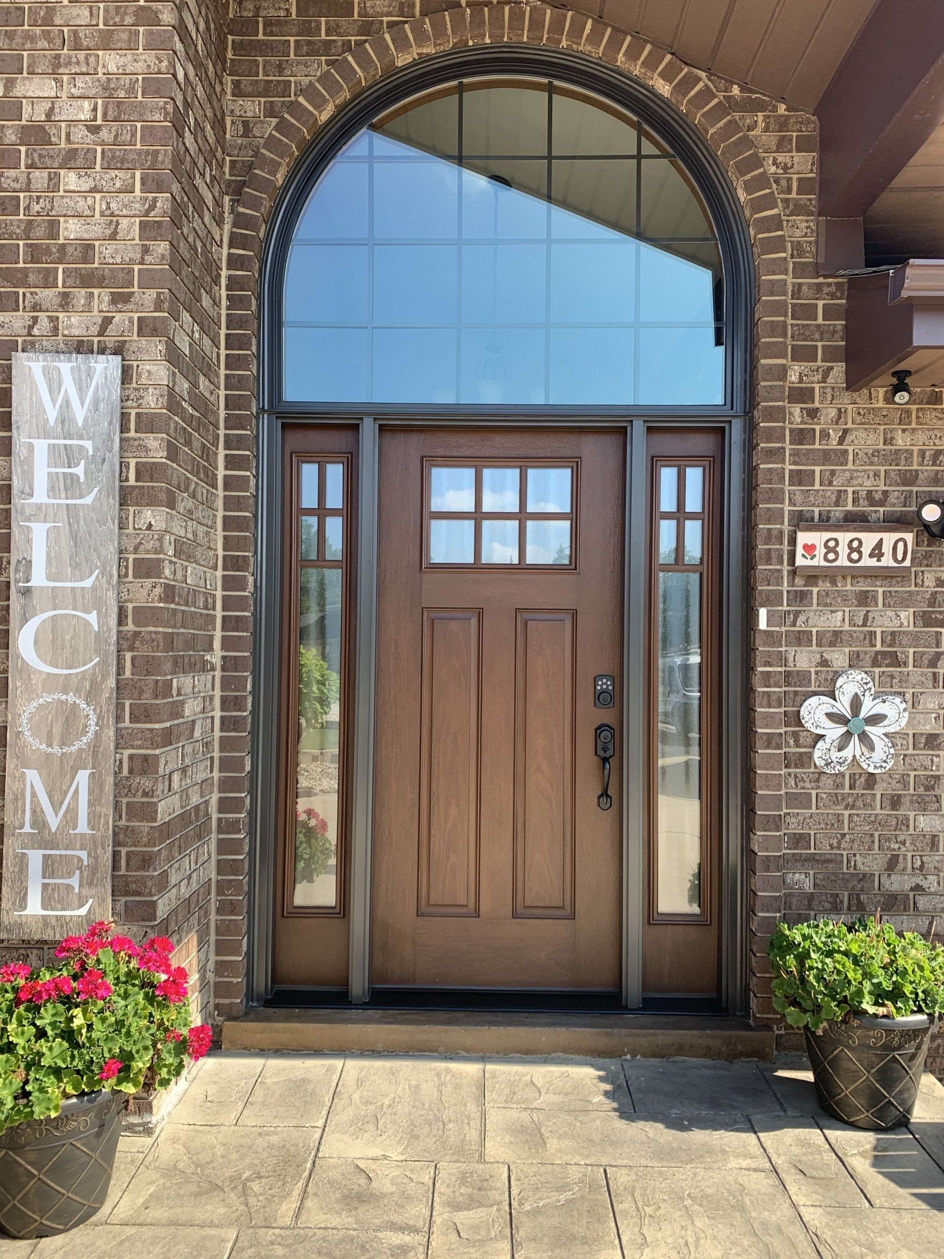 The front door of a brick house with a welcome sign in front of it